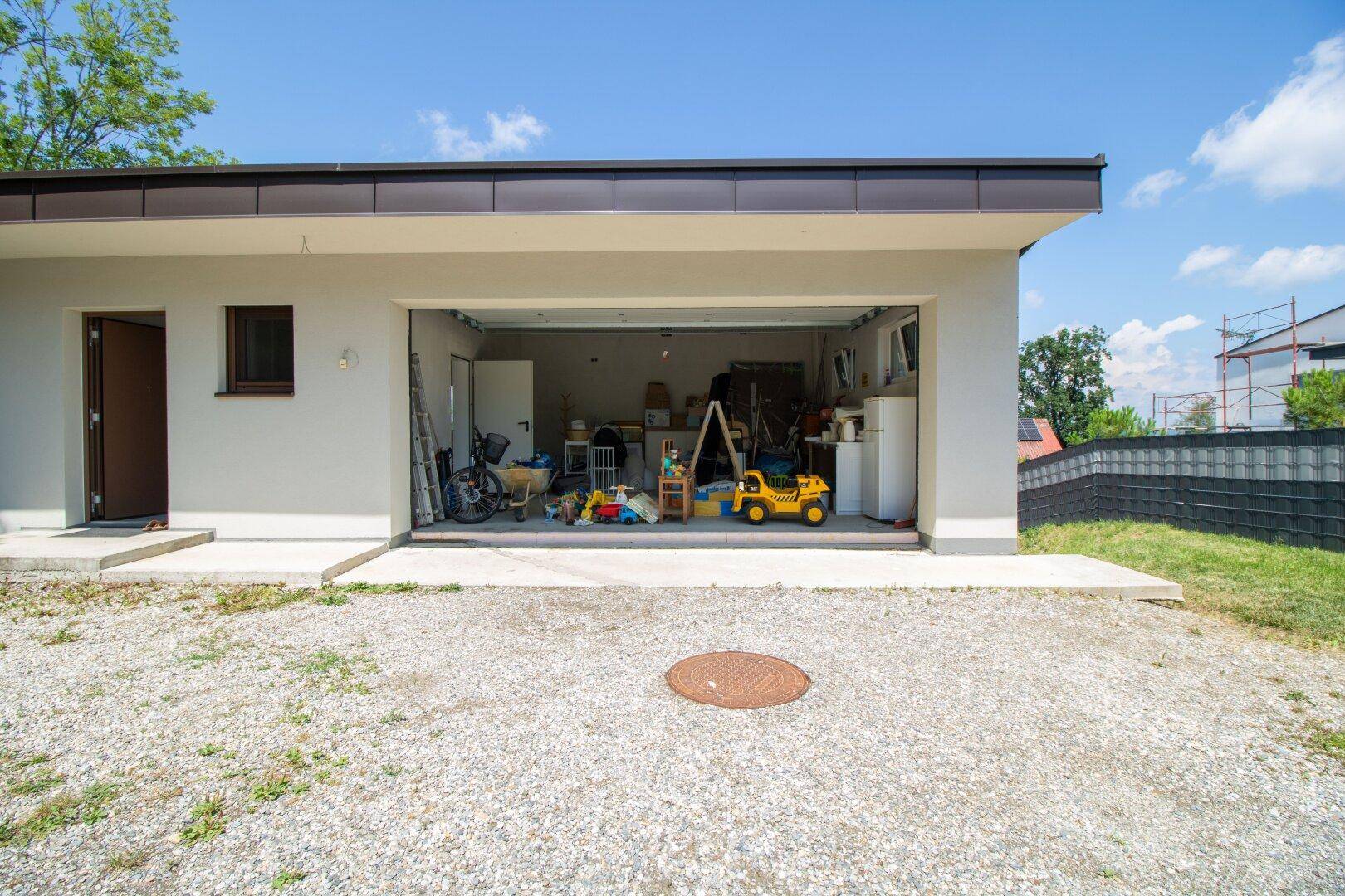 Außenansicht einer Garage mit offenem Tor, die einen unaufgeräumten Innenraum zeigt.
