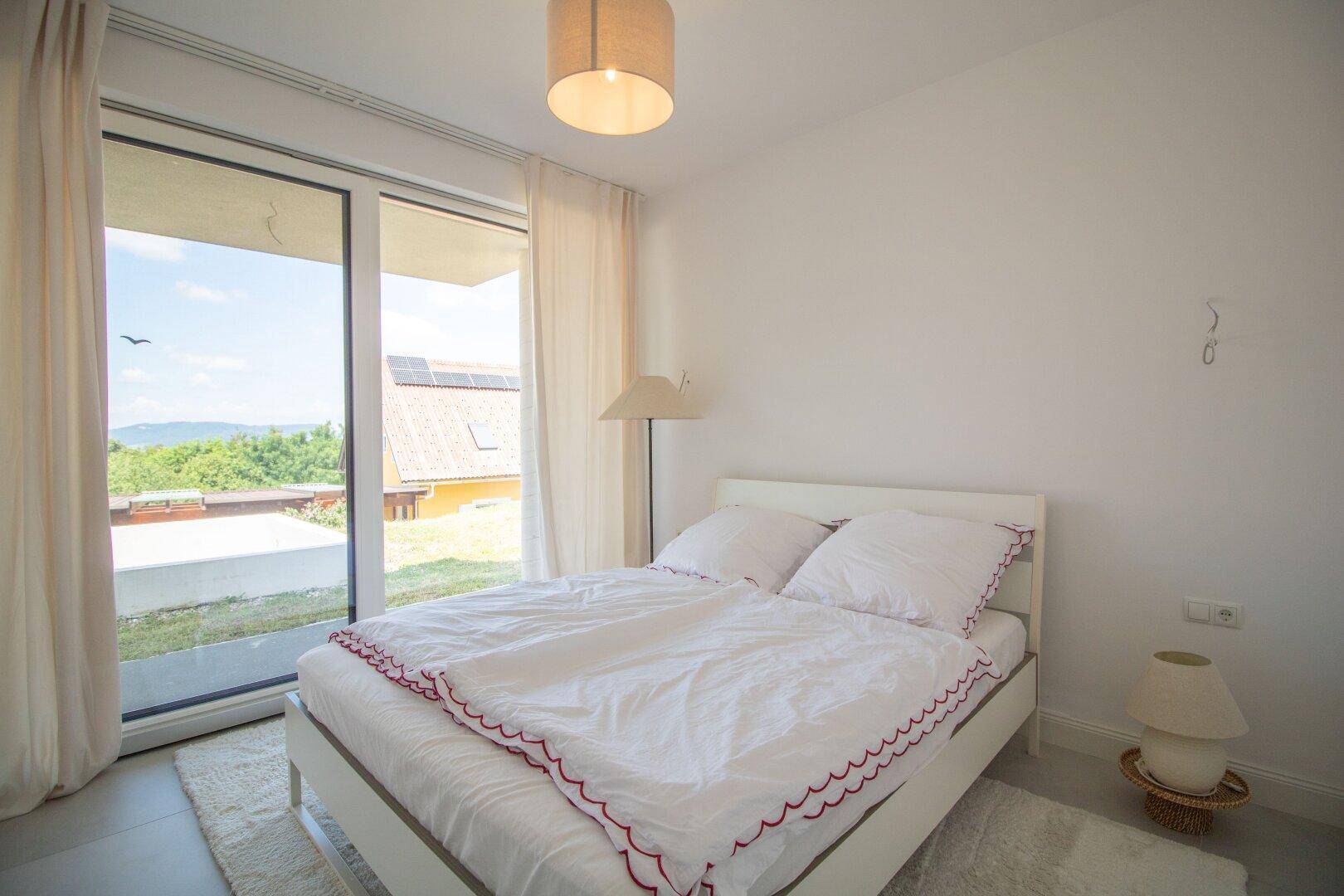 Schlafzimmer mit Doppelbett, großen Schiebetüren und Blick auf die umliegende Landschaft.