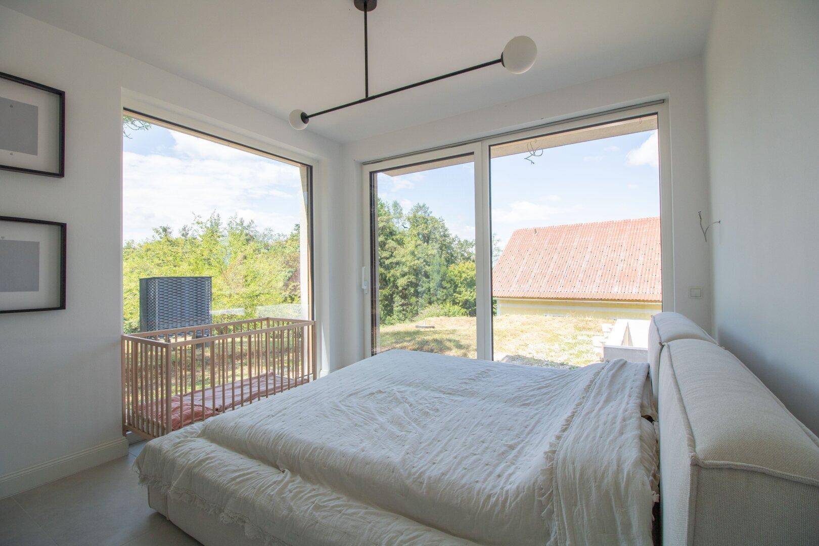 Helles Schlafzimmer mit großen Fenstern, die viel Tageslicht und einen weiten Blick bieten.