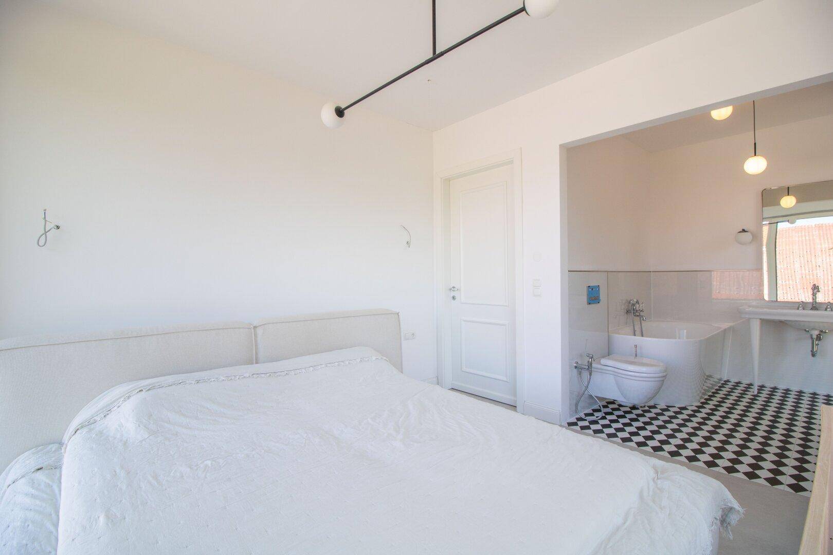 Schlafzimmer mit angrenzendem Badezimmer, ausgestattet mit WC und Badewanne.