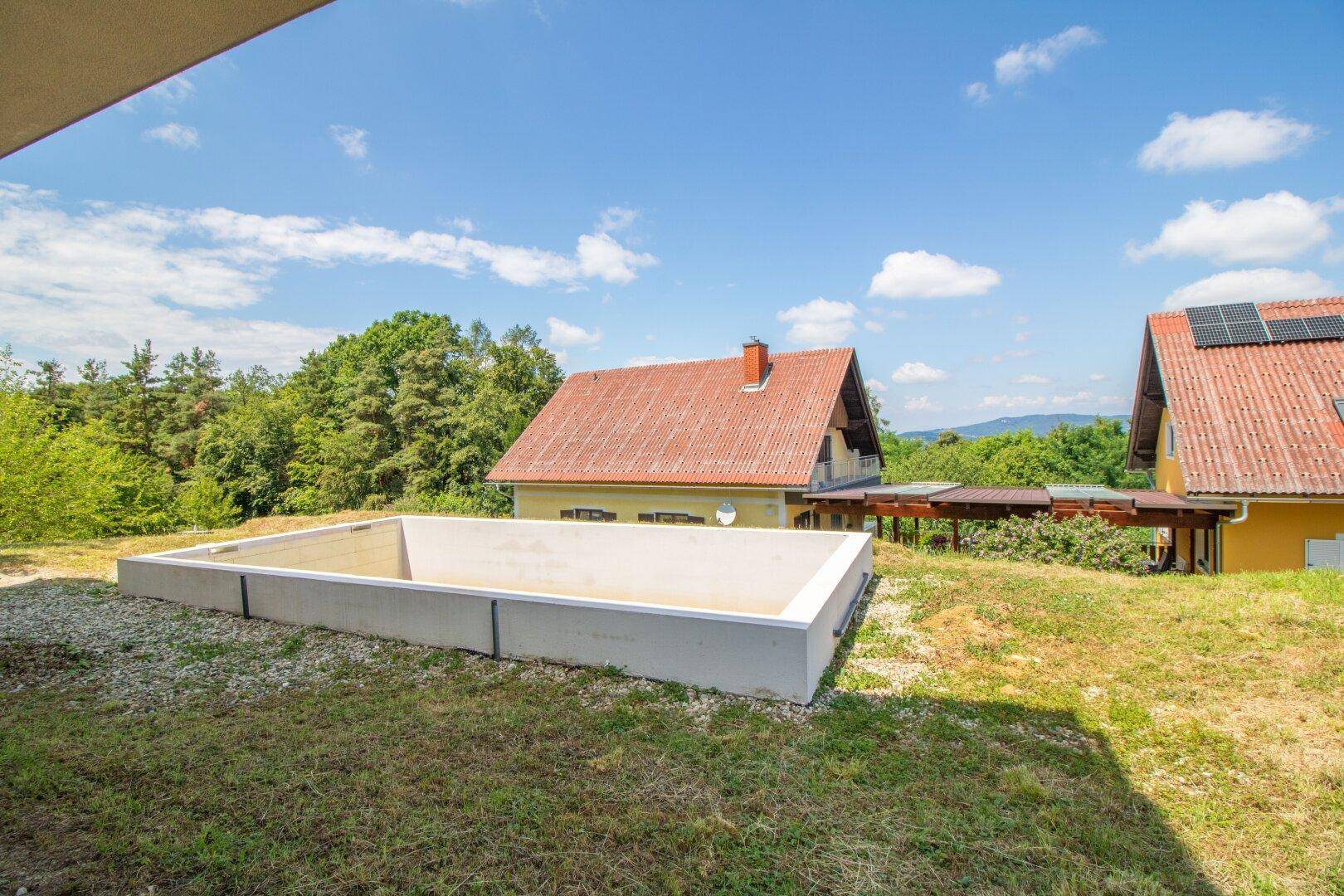 Garten mit unfertigem Poolbereich und weitem Blick auf die grüne Umgebung.