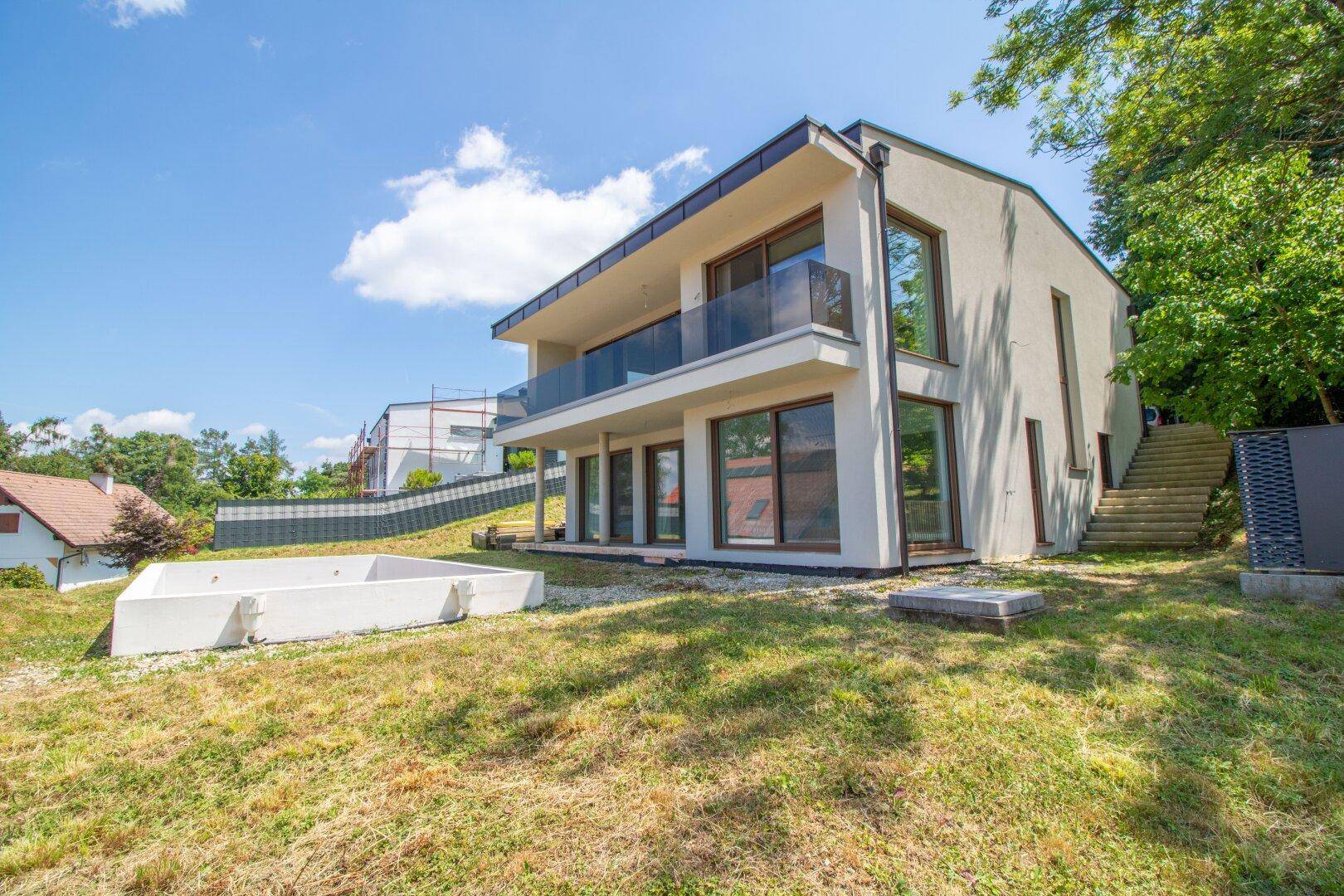 Moderne Villa mit mehreren Balkonen und Terrassen in einer grünen Umgebung.