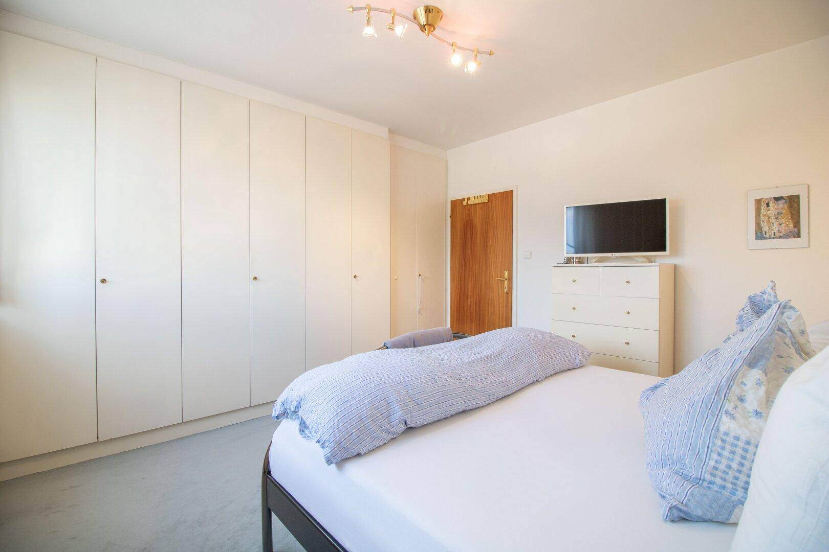 Schlafzimmer mit Einbauschränken, Doppelbett und Fernseher.
