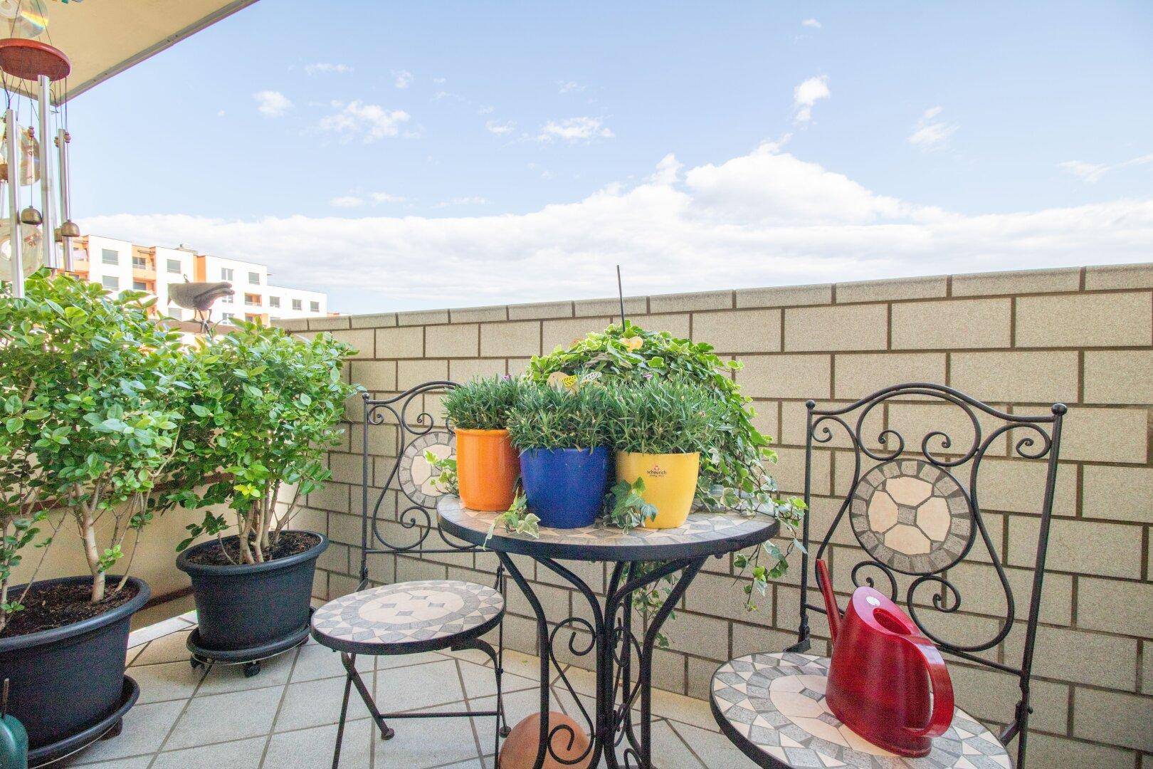 Gemütlicher Balkon mit Sitzgelegenheiten, Pflanzen und Blick auf die Umgebung.