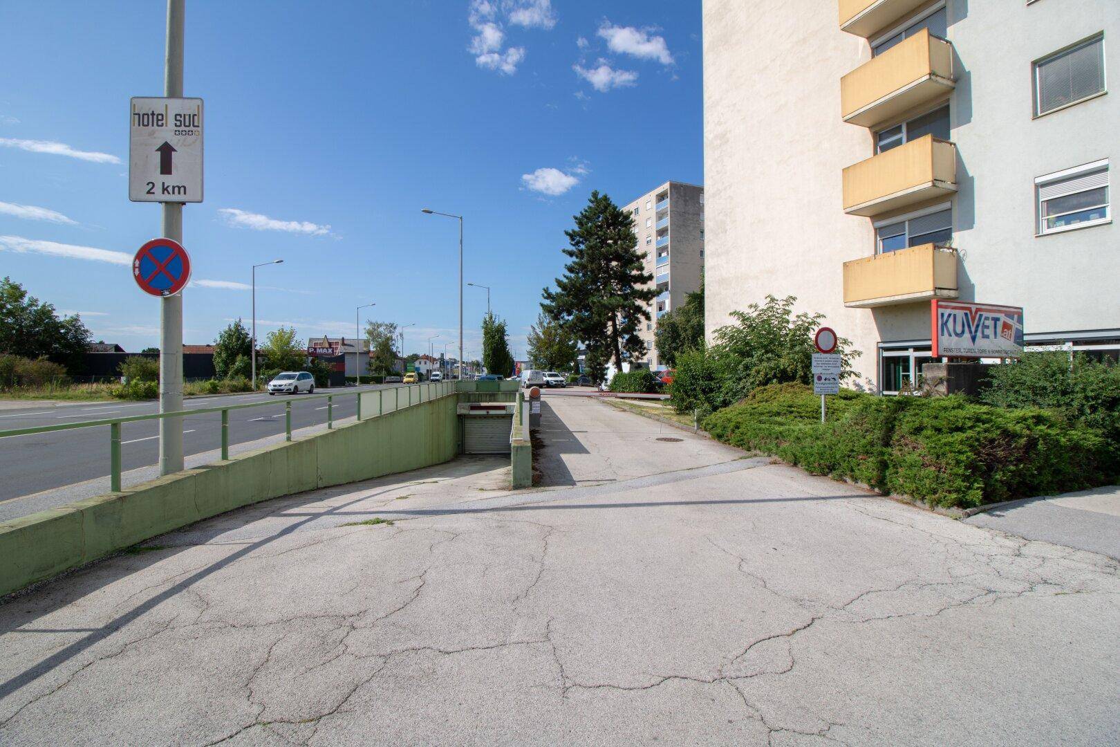 Zufahrt zu einer Tiefgarage neben einem Mehrfamilienhaus mit umliegender Straße.