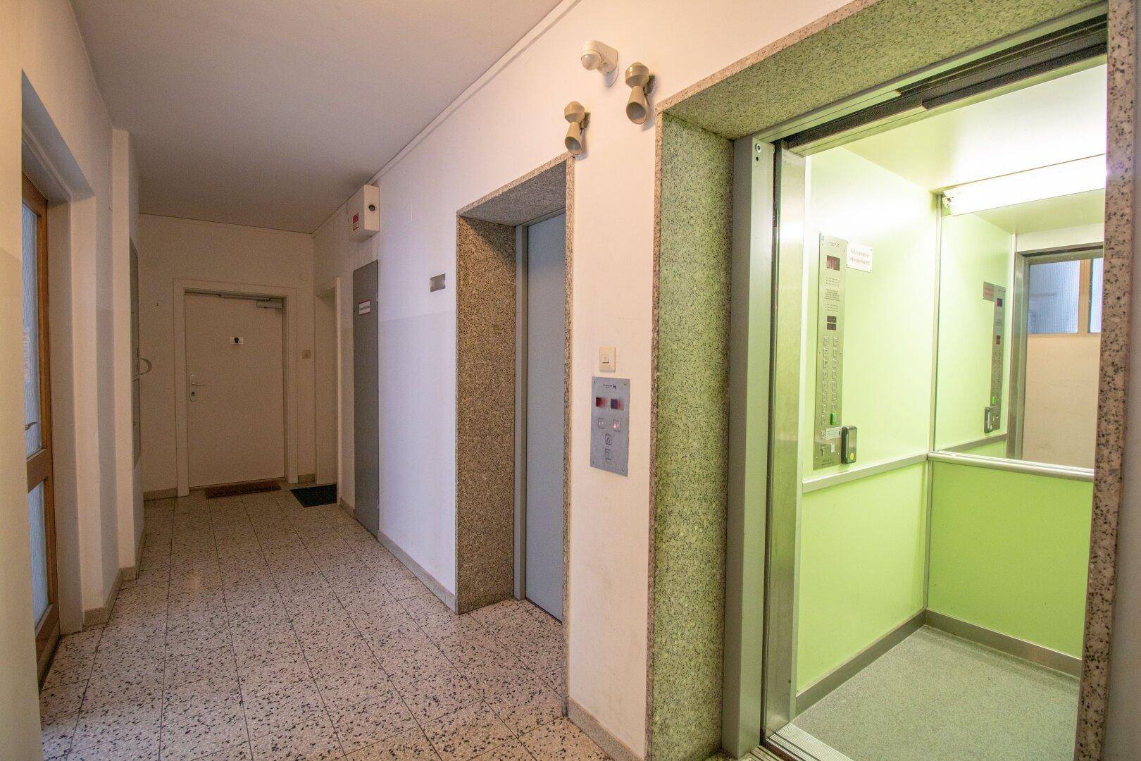 Geräumiger Flur mit Aufzug und Fliesenboden, der Zugang zu den Wohneinheiten bietet.