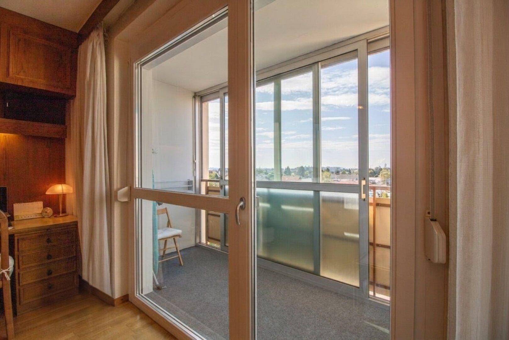 Wohnzimmer mit Zugang zur verglasten Loggia und weitem Blick nach draußen.