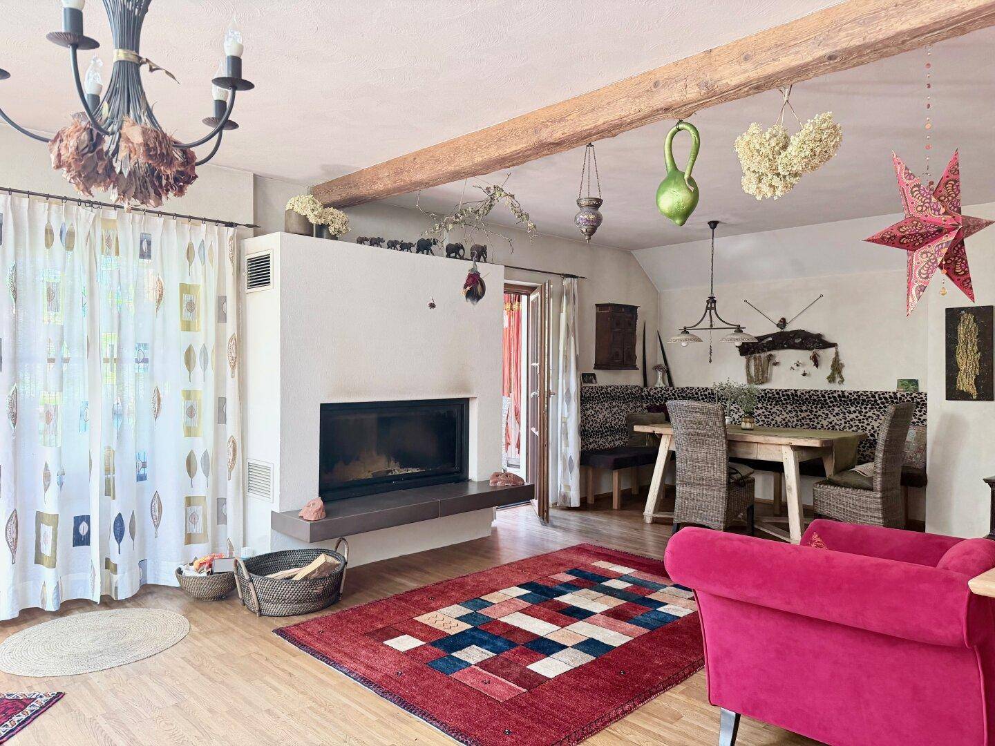 Geräumiger Wohn- und Essbereich mit Kamin, Holzbalken und traditionellem Teppich.