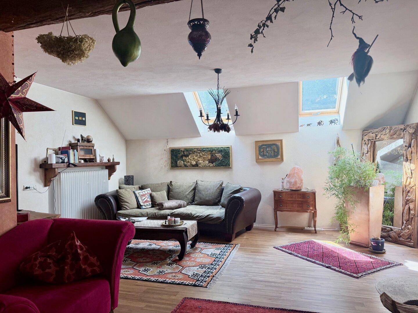 Gemütliches Wohnzimmer im Dachgeschoss mit Dachfenstern, Sofa und farbenfrohen Teppichen.