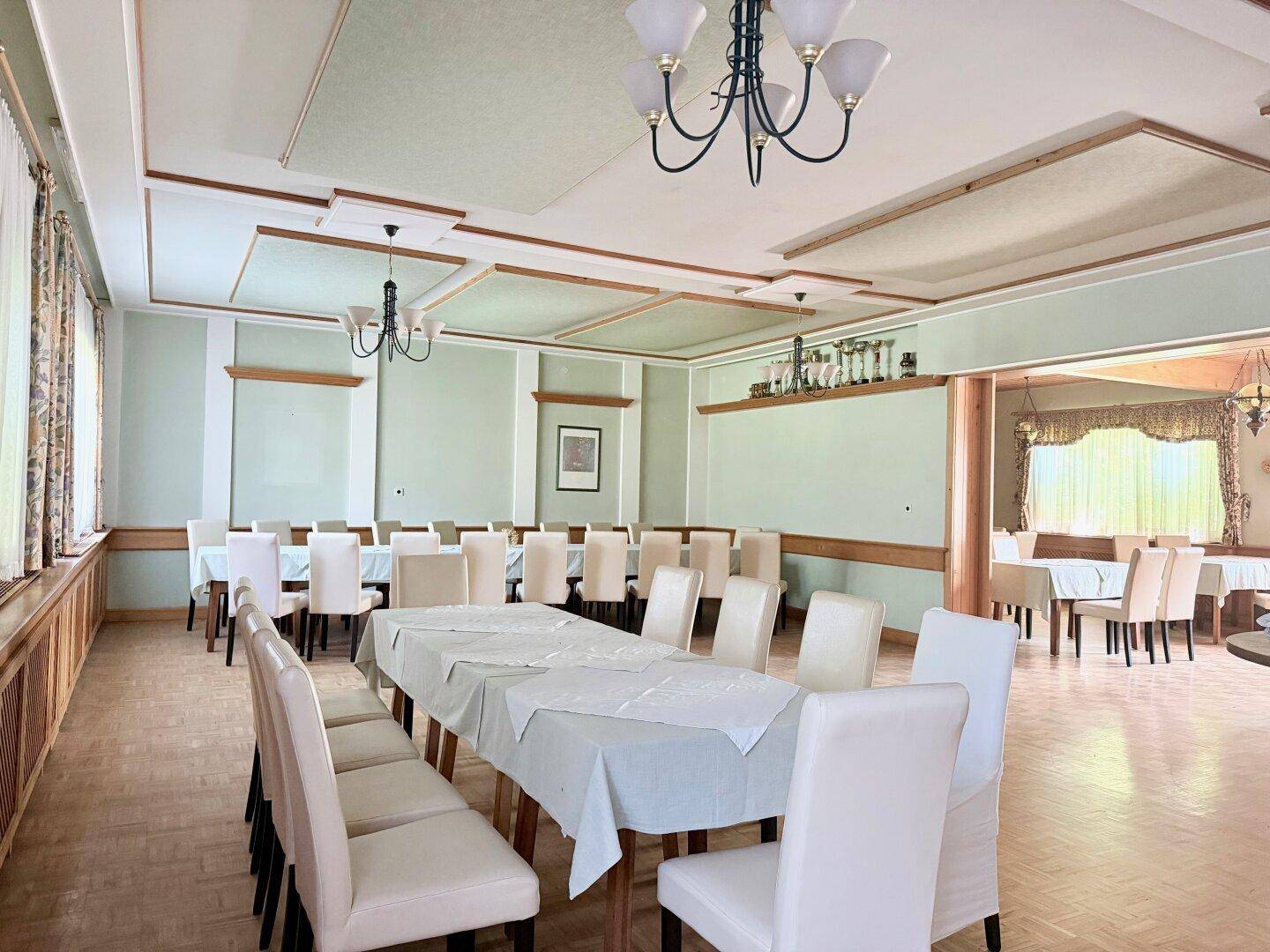 Geräumiger Speisesaal mit hellgrünen Wänden, Holzelementen und vielen Sitzgelegenheiten.