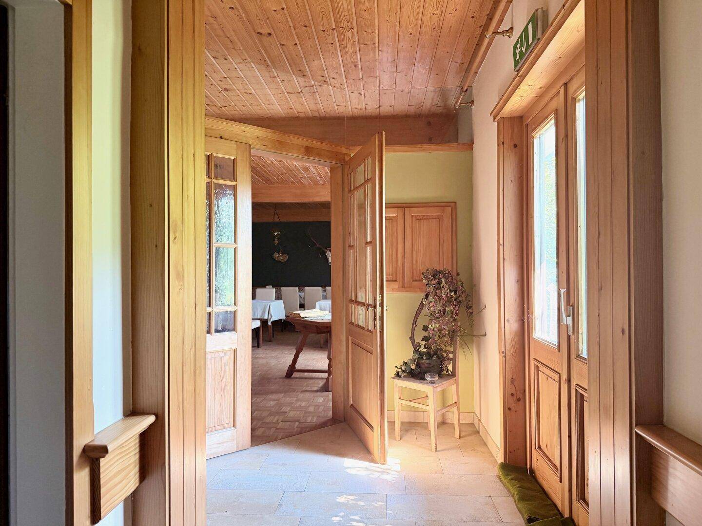 Eingangsbereich mit Holztüren, Holzboden und Zugang zu weiteren Räumen.