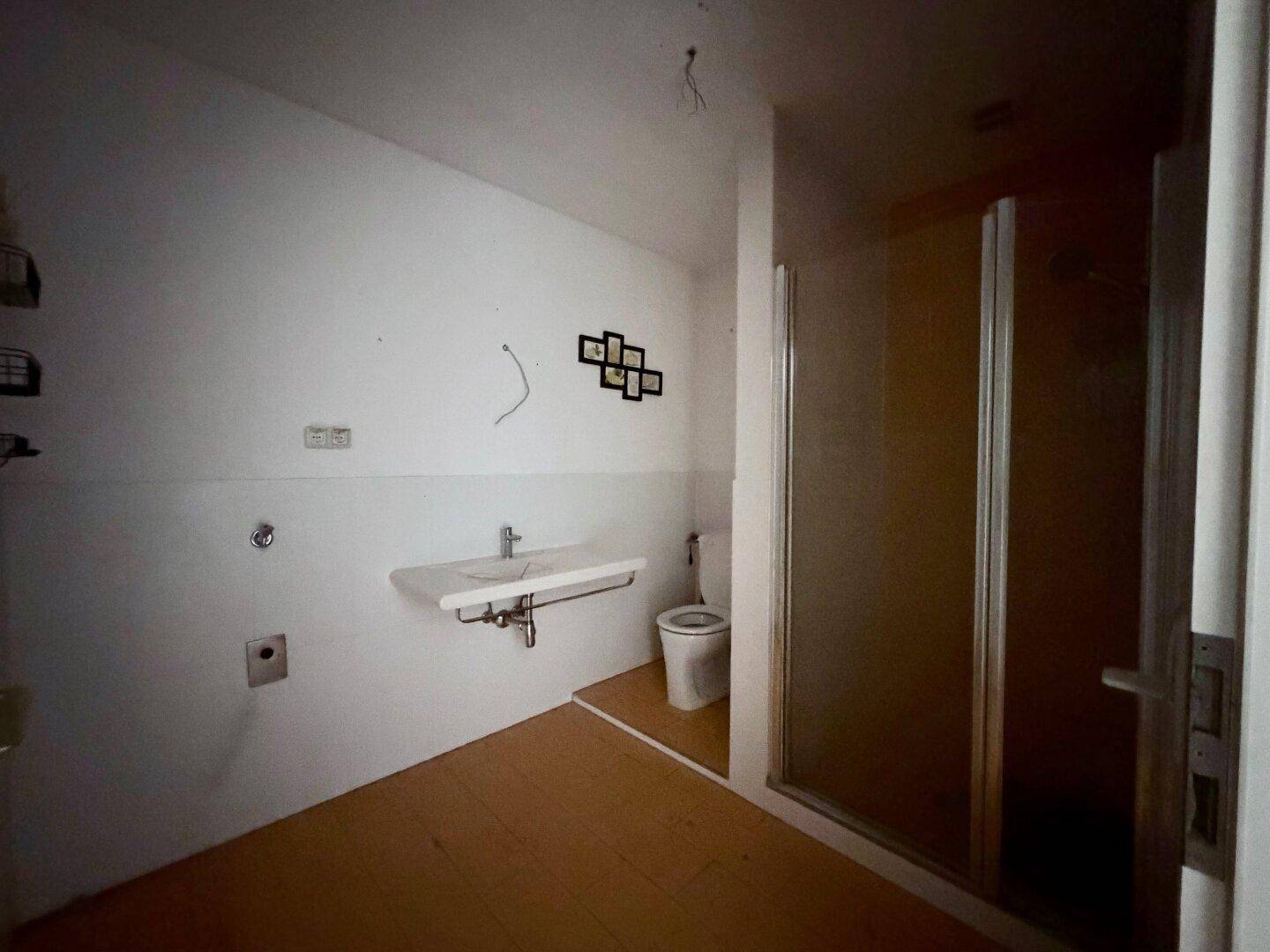 Badezimmer in Renovierung mit Waschbecken, Toilette und Duschkabine, noch unfertig.