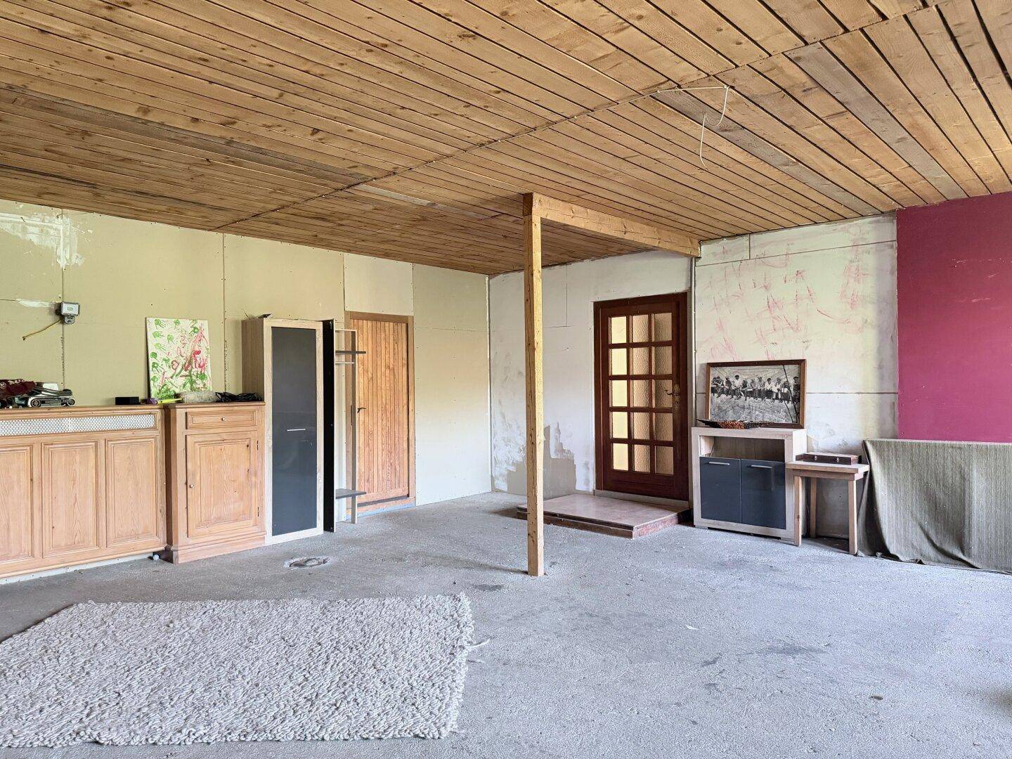 Großer, unfertiger Raum mit Holzdecke und Betonboden, vielseitig nutzbar als Abstellraum.