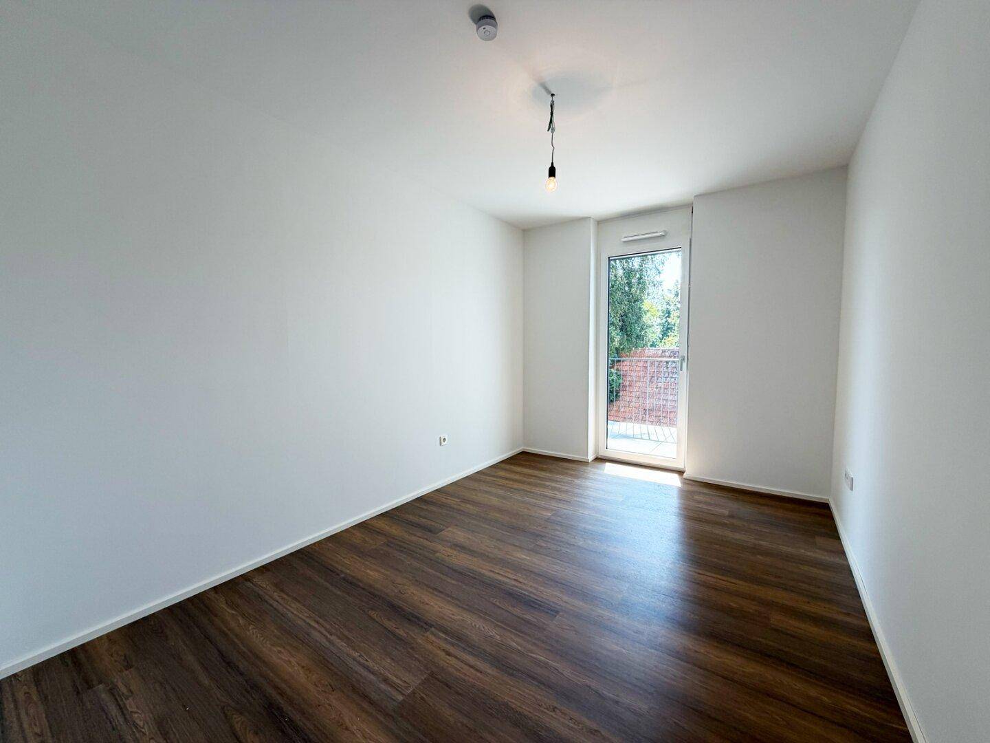 Schlafzimmer mit Laminatboden und Zugang zu einem Außenbereich, bietet eine angenehme Wohnatmosphäre.