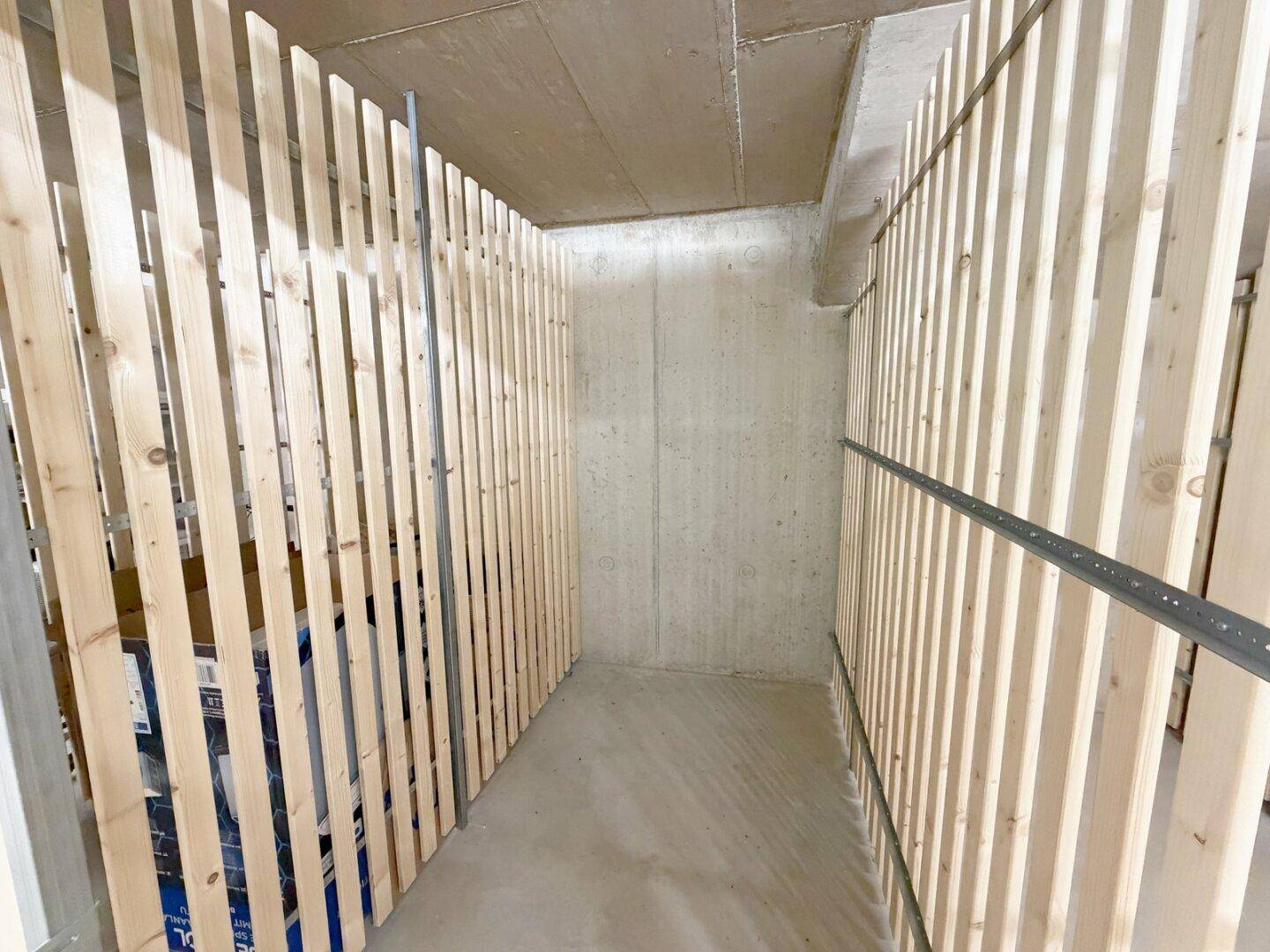 Kellerabteil mit Holzlattenwänden, bietet zusätzlichen Stauraum für persönliche Gegenstände.