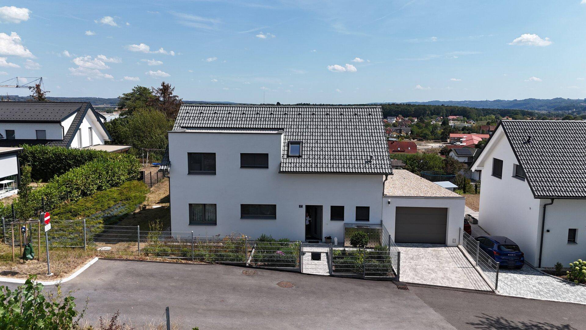 Moderne Hausfassade von der Straße aus gesehen mit Garage, Einfahrt und gepflegtem Eingangsbereich.