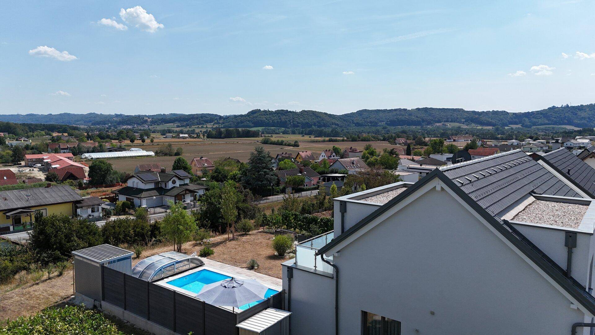 Panoramablick vom Haus über den Pool und den Garten auf die weite, grüne Landschaft.