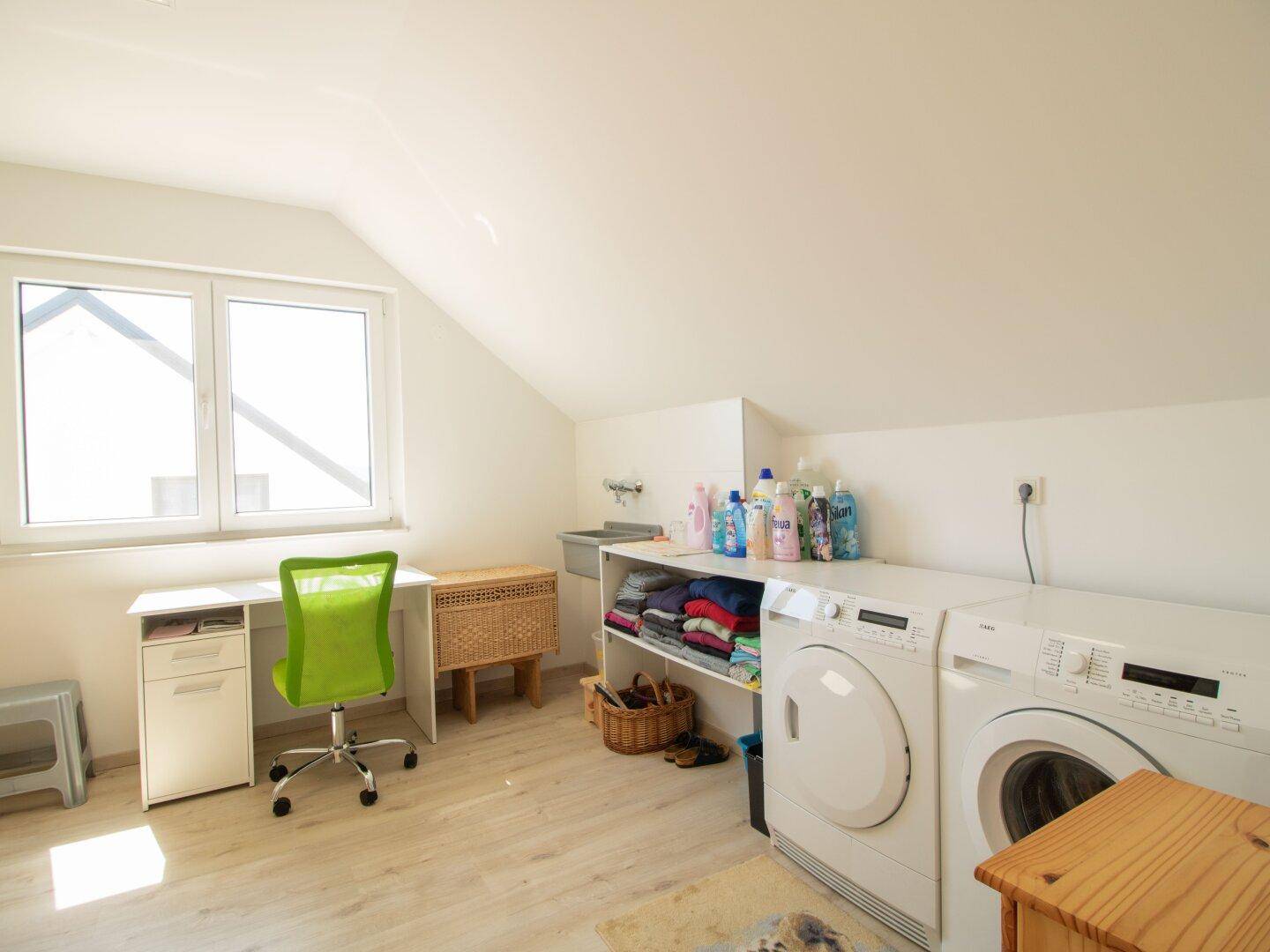 Praktischer Hauswirtschaftsraum im Dachgeschoss mit Waschmaschine, Trockner und viel Stauraum.