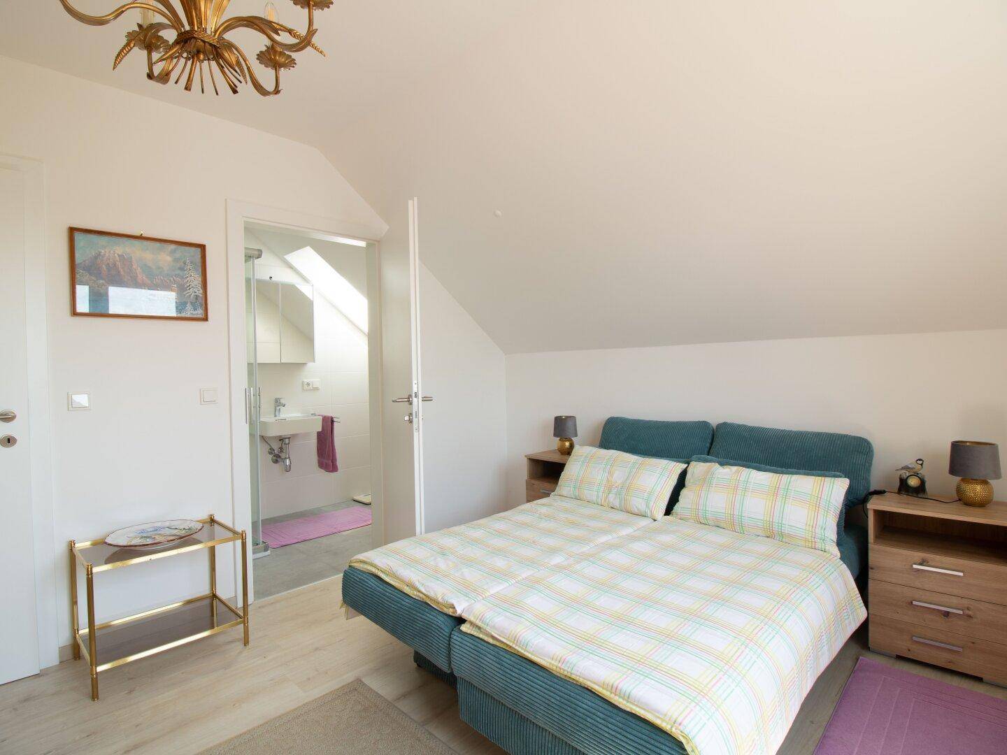 Gemütliches Schlafzimmer im Dachgeschoss mit Doppelbett und direktem Zugang zu einem eigenen Badezimmer.