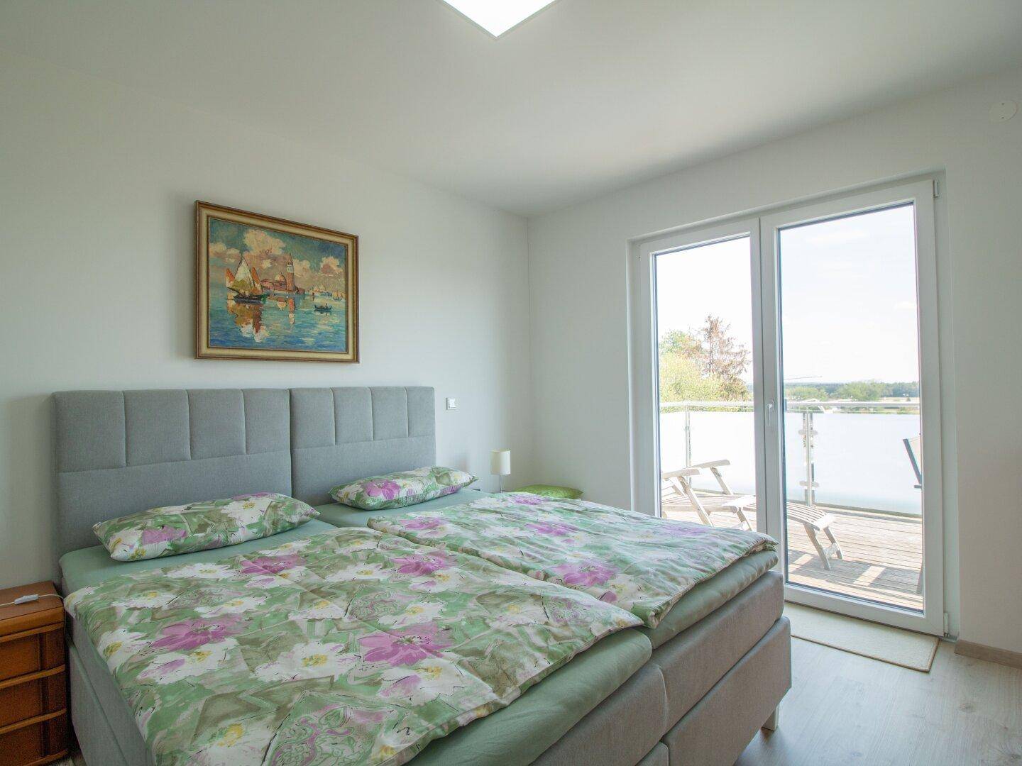 Helles Schlafzimmer mit Doppelbett und direktem Zugang zu einem Balkon mit schöner Aussicht.
