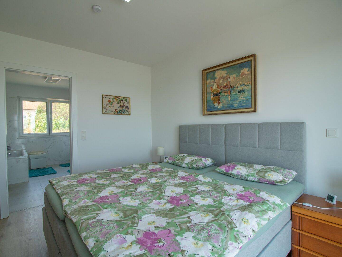 Komfortables Schlafzimmer mit Doppelbett und direktem Zugang zu einem modernen Badezimmer.