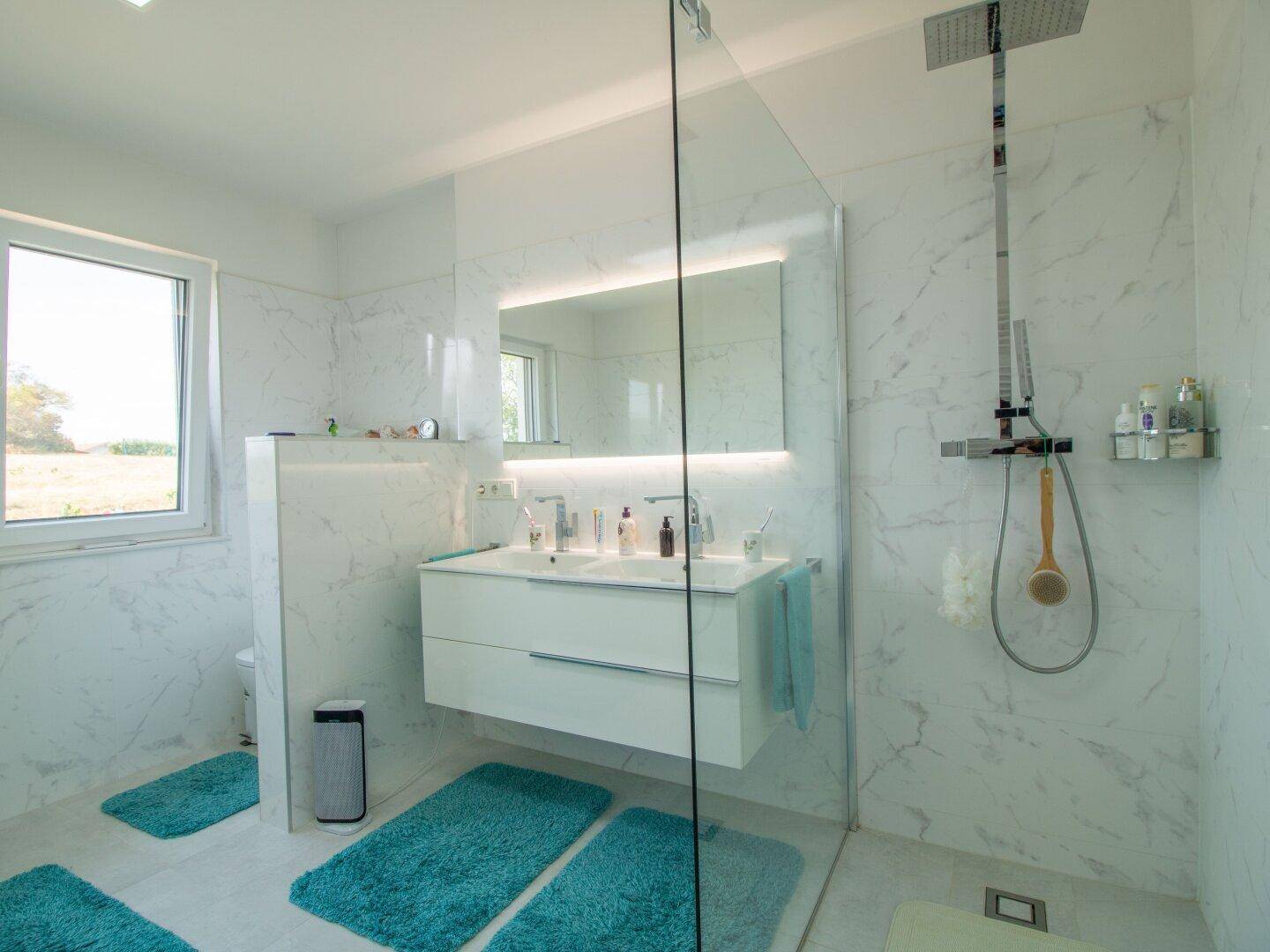 Elegantes Badezimmer mit begehbarer Dusche, Doppelwaschbecken und großem Fenster.