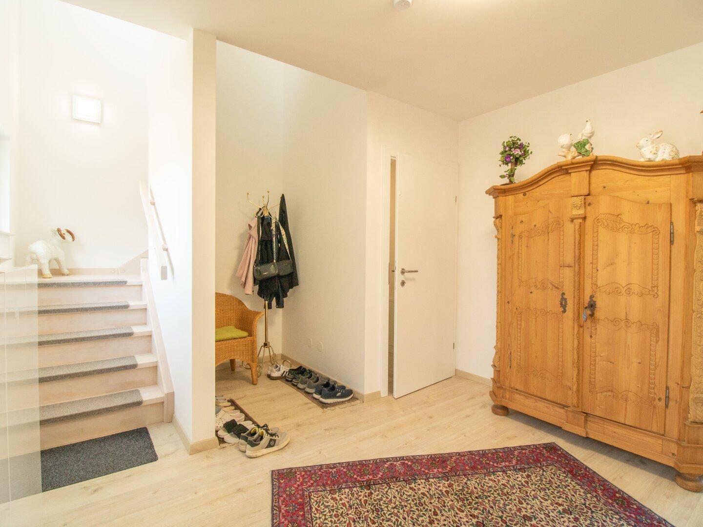 Geräumiger Flur mit Holzschrank, Schuhablage und Zugang zum Treppenhaus.