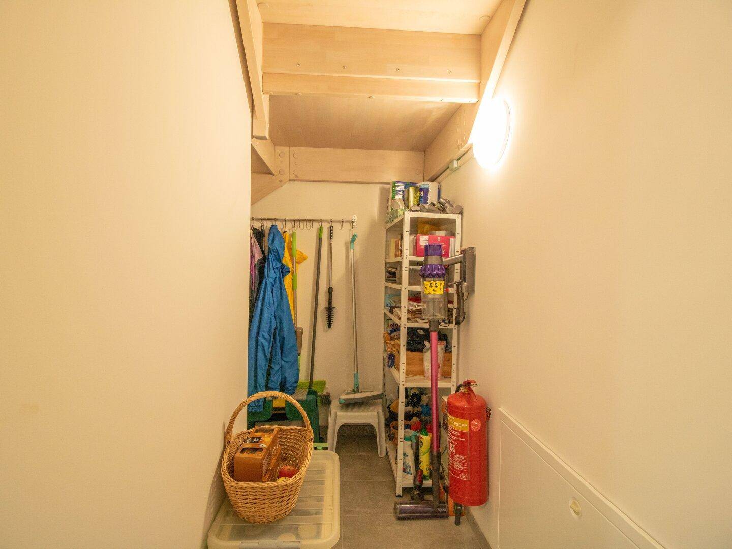 Praktischer Abstellraum unter der Treppe mit Regalen für Reinigungsutensilien und Vorräte.