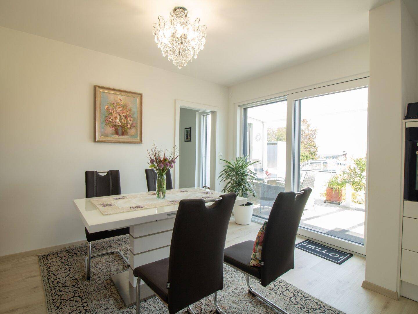 Eleganter Essbereich mit großem Esstisch, modernen Stühlen und Zugang zur Terrasse.