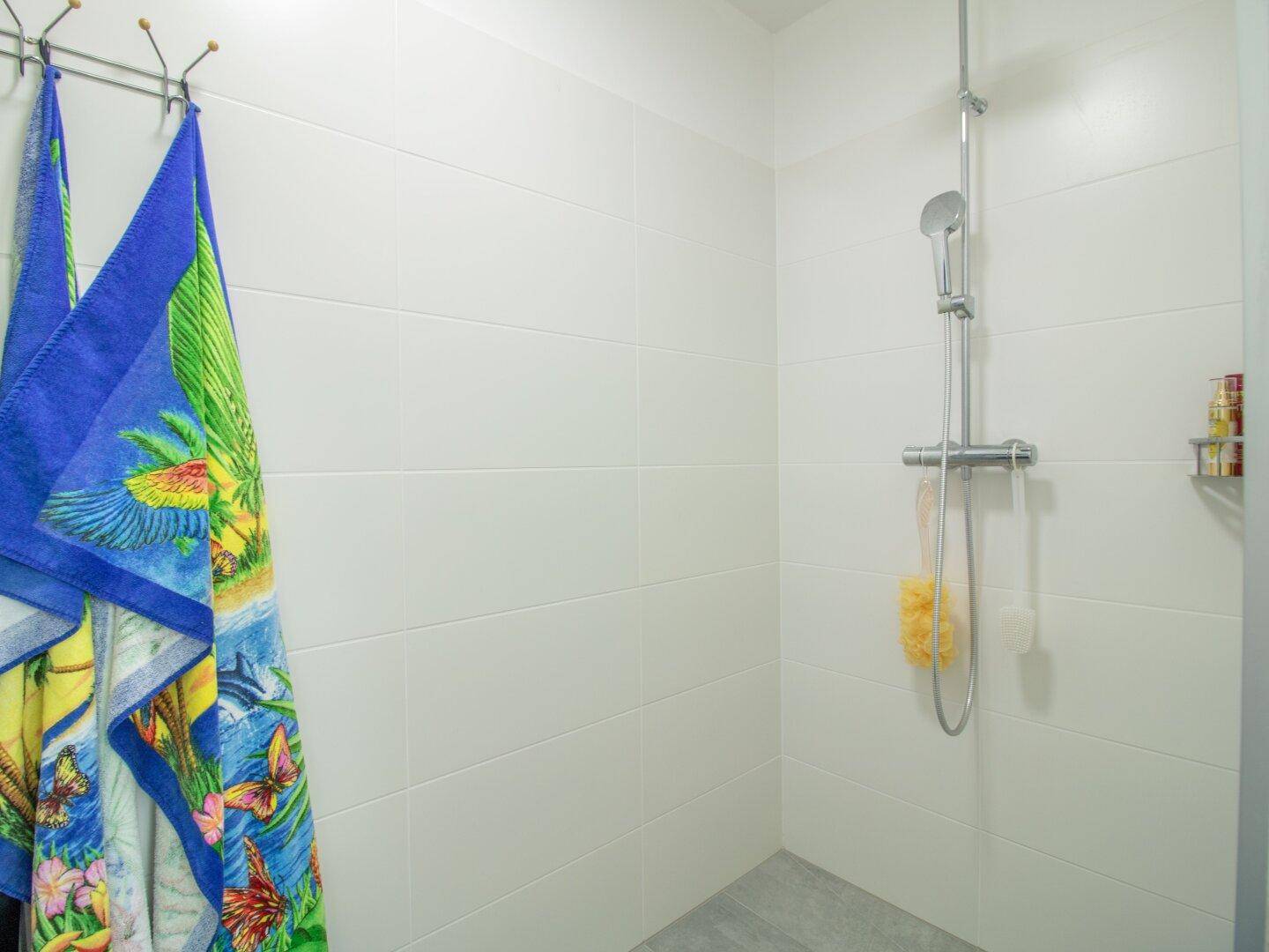 Modernes Badezimmer mit weiß gefliesten Wänden und einer geräumigen Dusche.