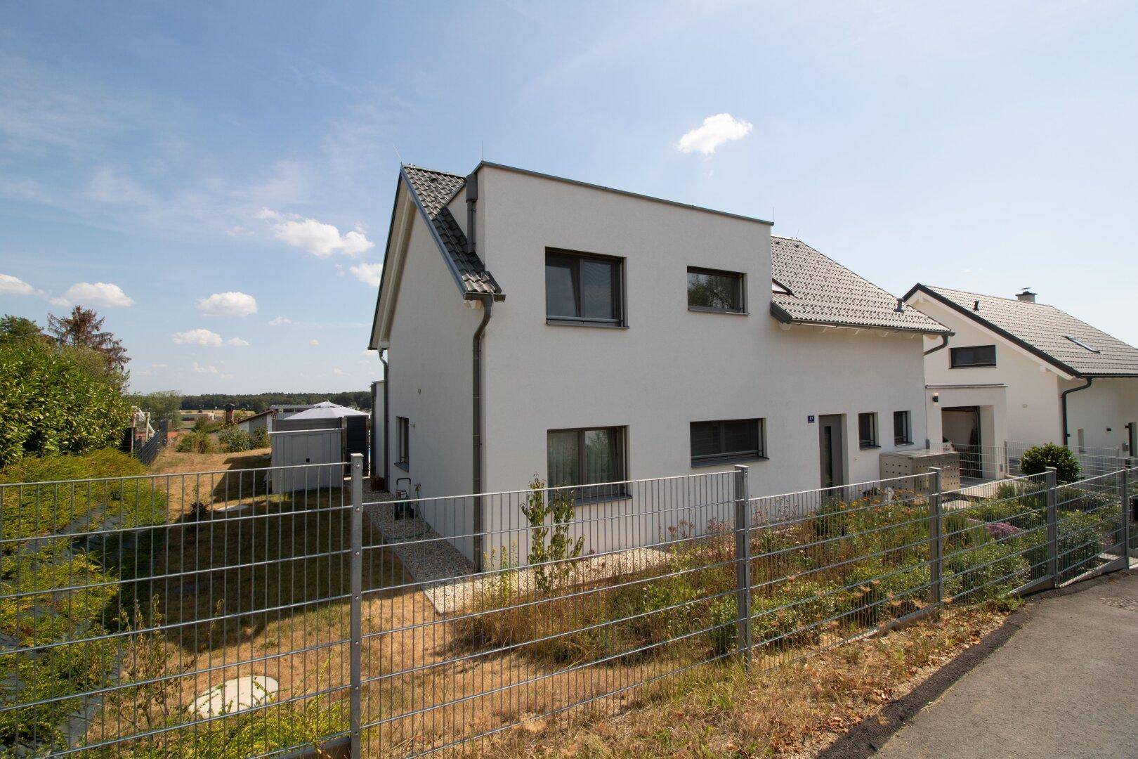 Rückansicht des modernen Einfamilienhauses mit Garten und Nebengebäude.