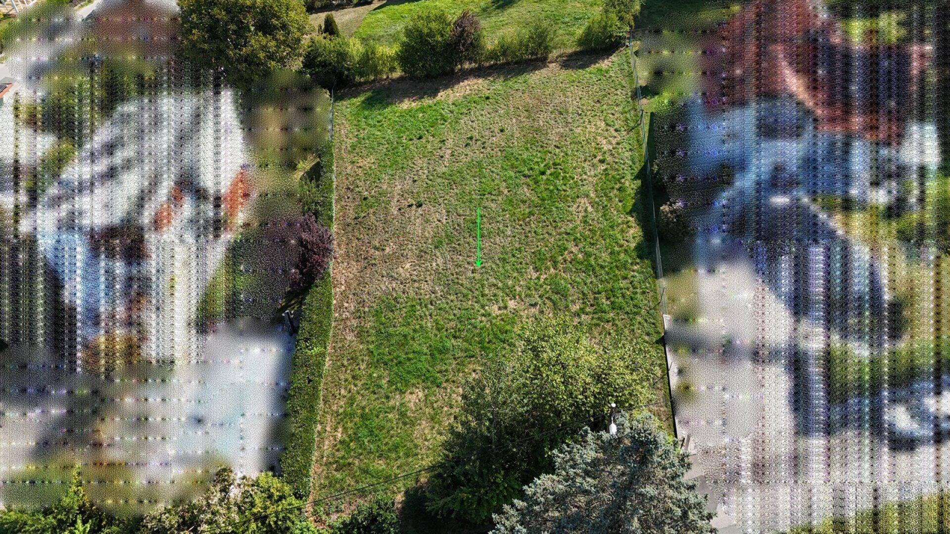 Direkte Draufsicht auf ein rechteckiges, grünes Grundstück mit umliegender Vegetation.