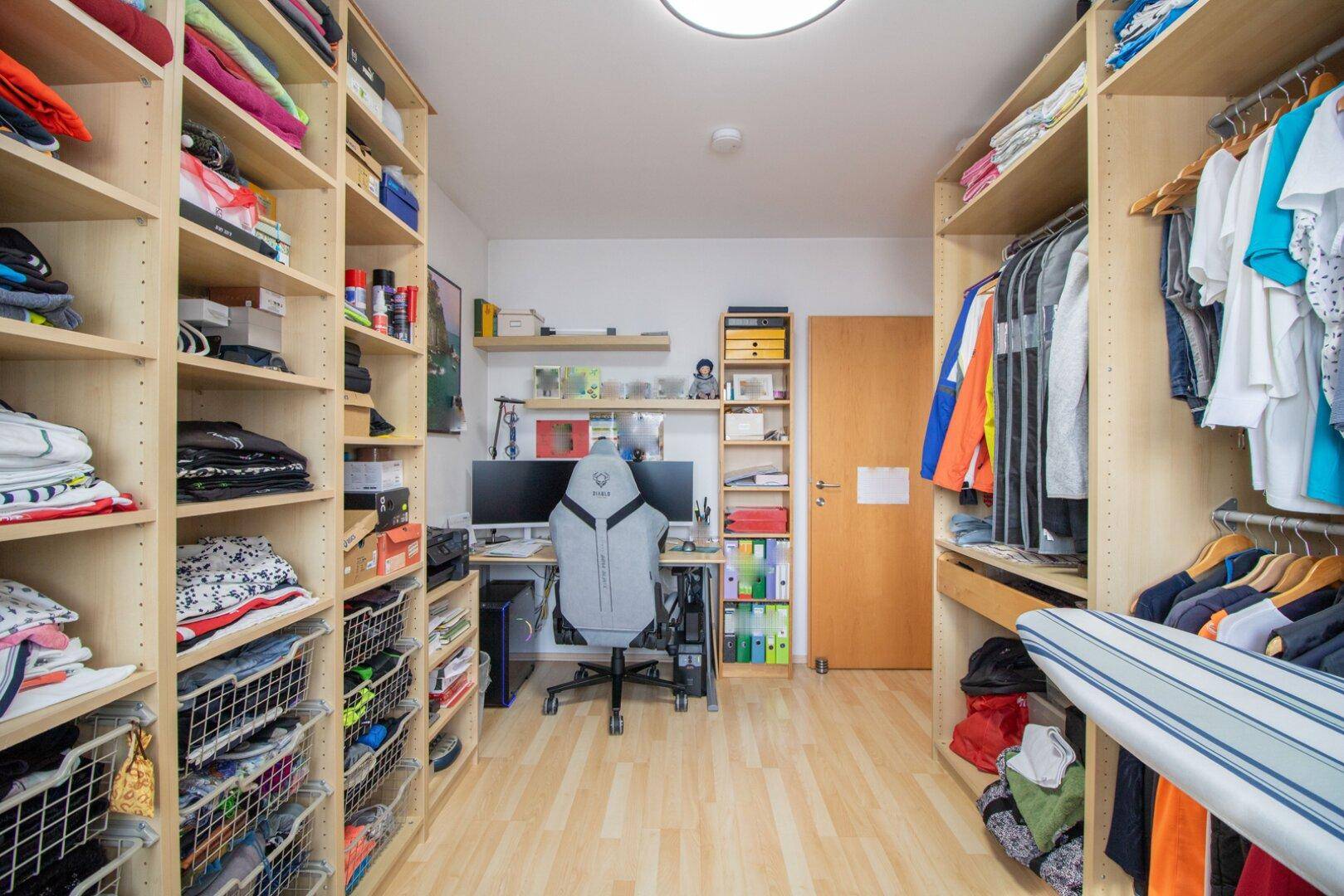 Praktischer begehbarer Kleiderschrank mit integriertem Arbeitsplatz und viel Stauraum für Kleidung.