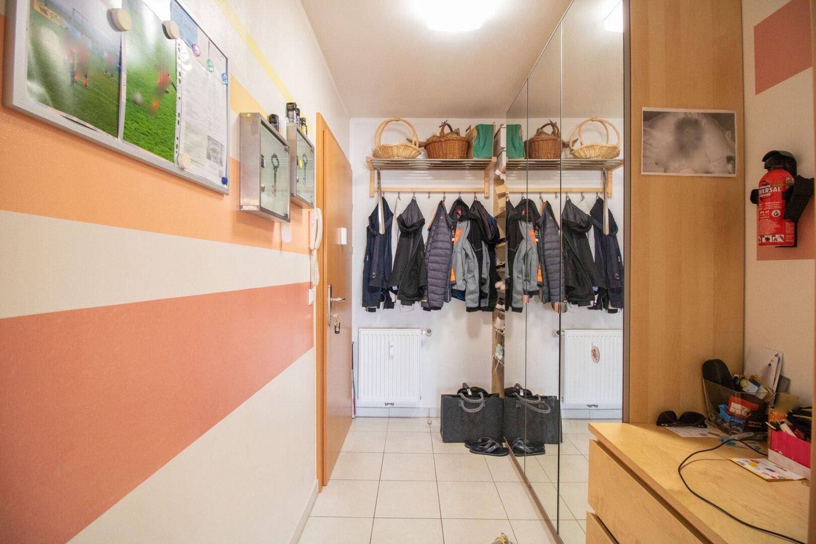 Heller Eingangsbereich mit Garderobe, großem Spiegel und praktischen Ablagemöglichkeiten.