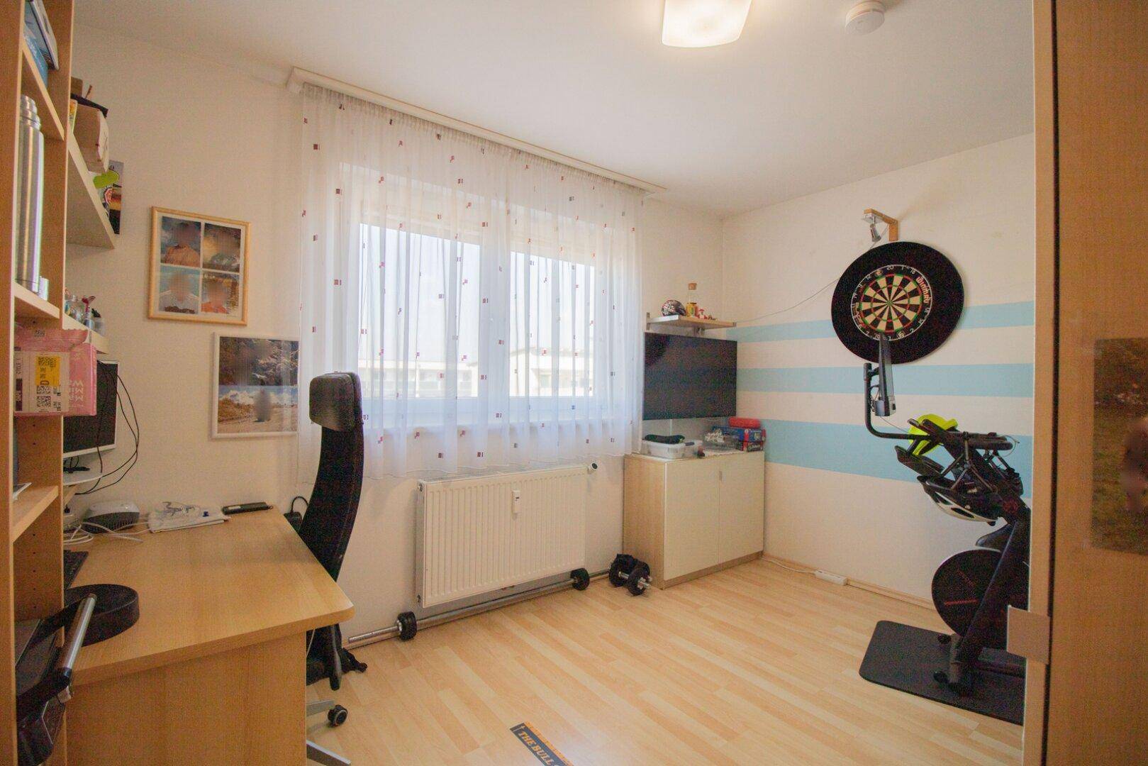 Vielseitiges Zimmer, eingerichtet als Büro mit Schreibtisch und als Fitnessbereich mit Heimtrainer.