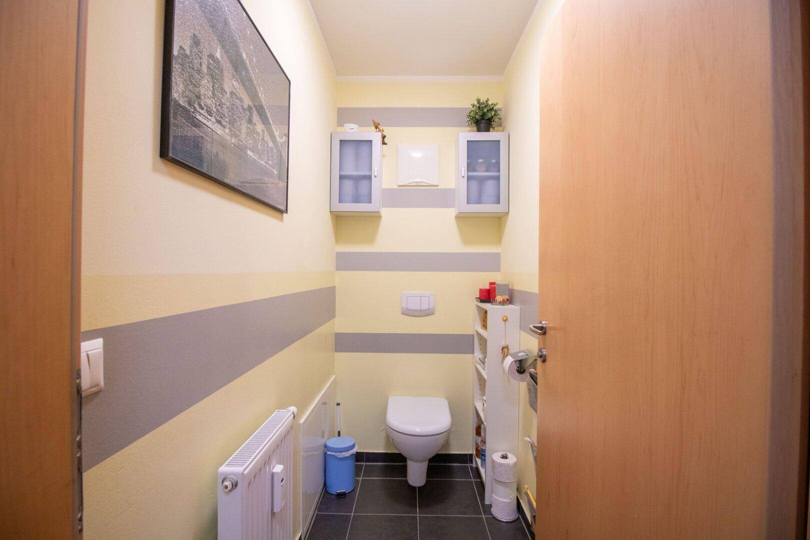 Modernes Gäste-WC mit wandhängender Toilette und farbigen Streifen an den Wänden.