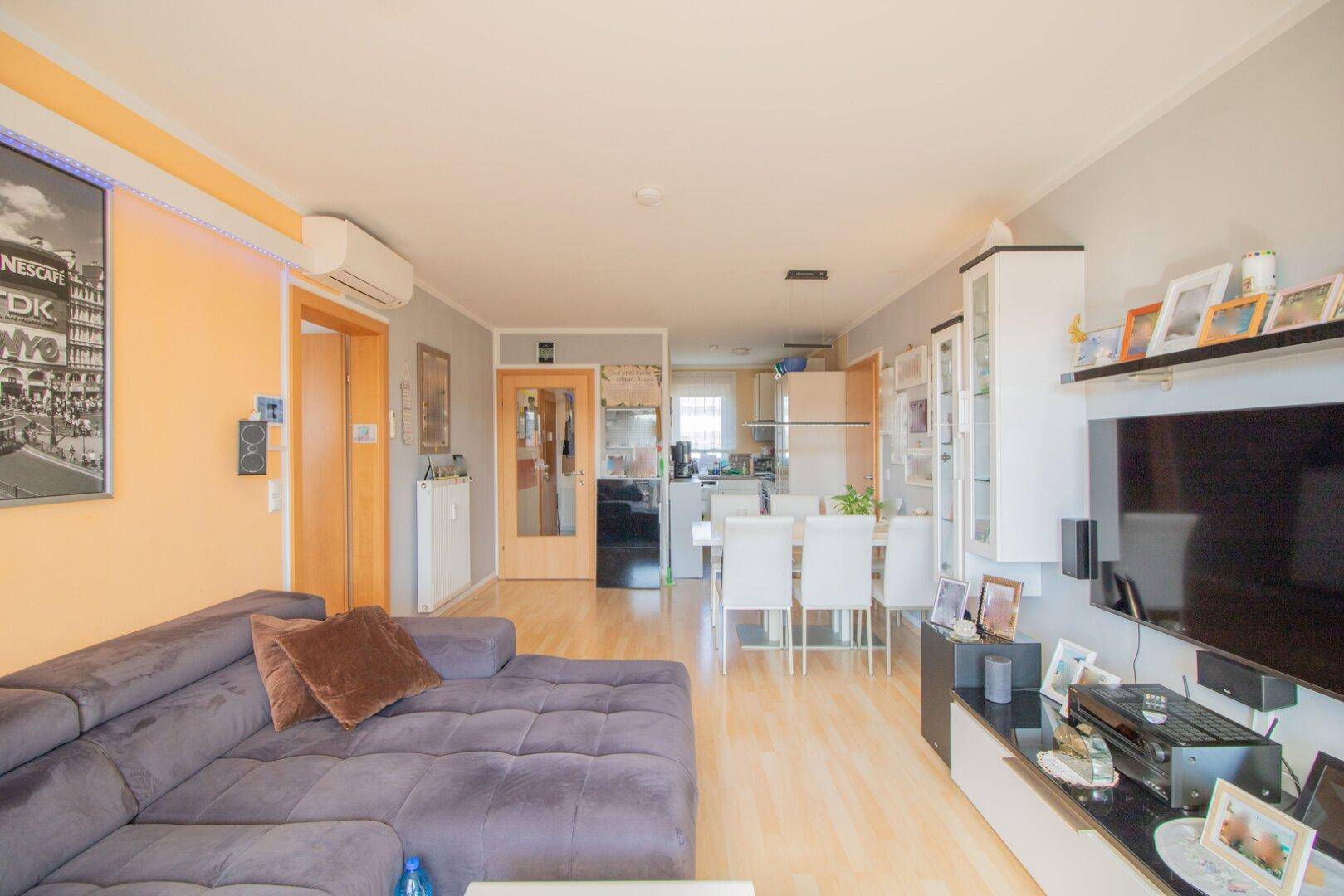 Offener Wohnbereich mit Essplatz und Blick in die Küche, ausgestattet mit Laminatboden und moderner Einrichtung.