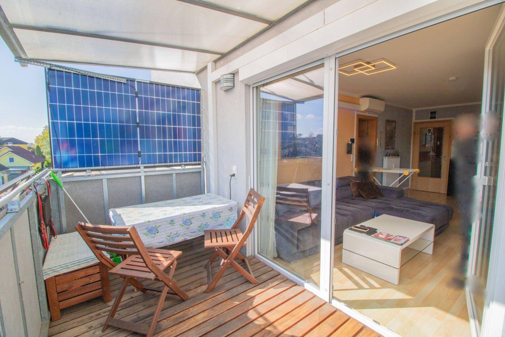 Geräumiger Balkon mit Holzboden und Schiebetür, der einen direkten Blick in den Wohnbereich ermöglicht.