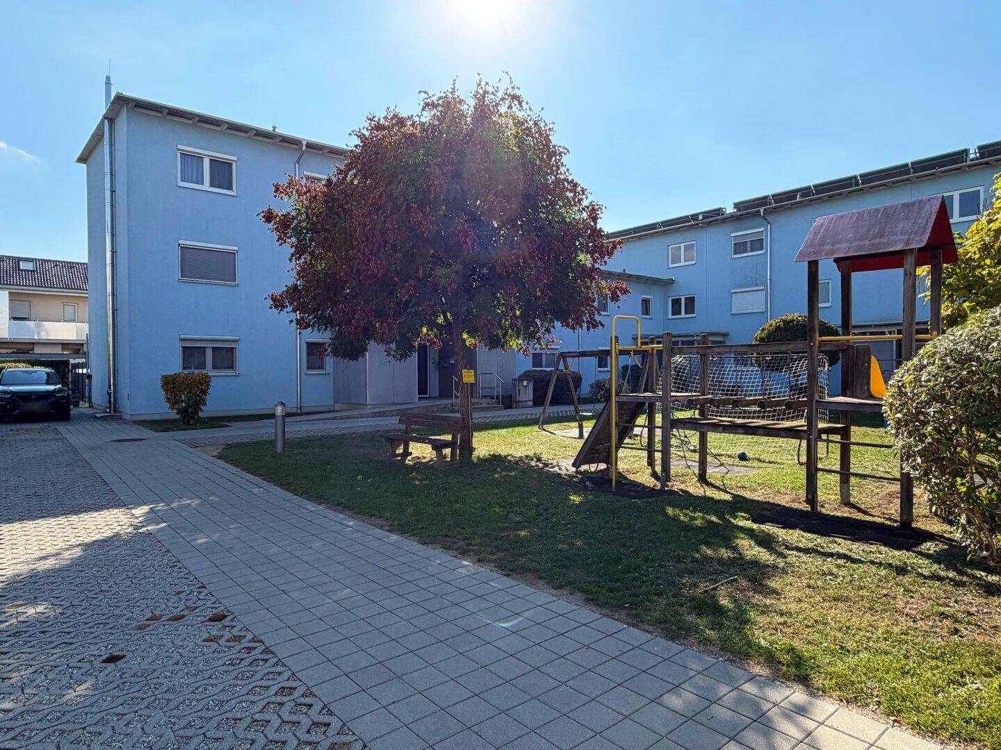 Außenansicht des Wohngebäudes mit einem Spielplatz und einer gepflegten Grünfläche für Kinder.