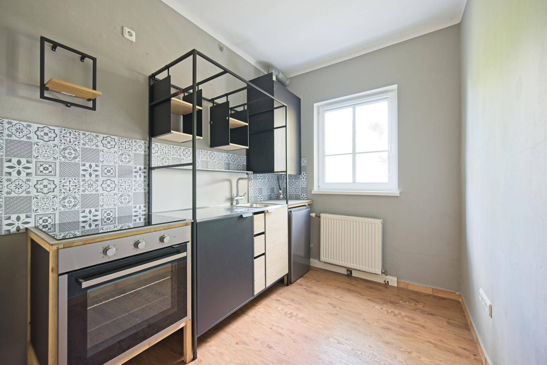 Moderne Küchenzeile mit industriellem Design, integriertem Ofen und dekorativen Fliesen.
