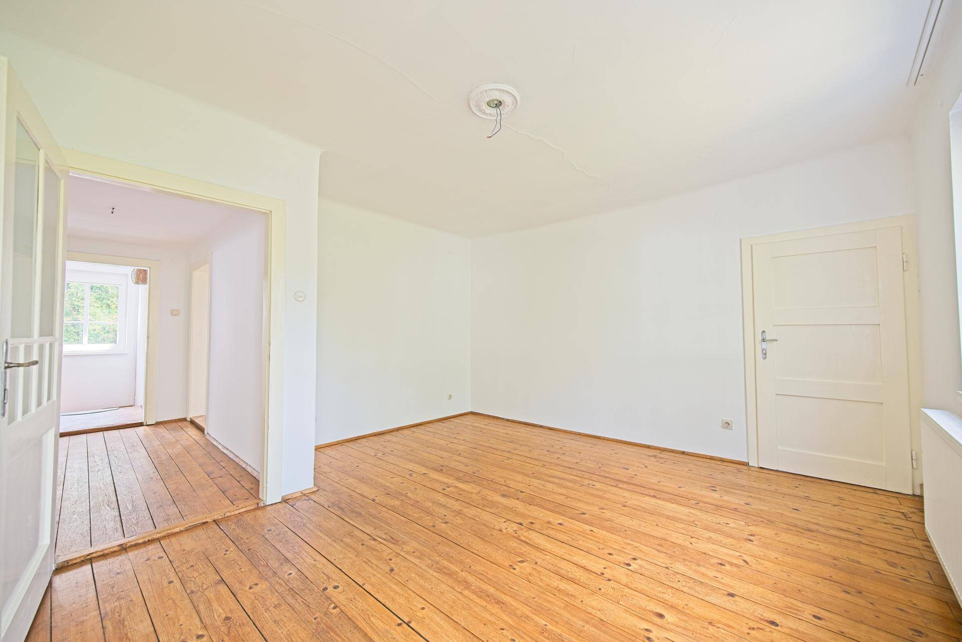 Freundliches Zimmer mit Dielenboden und weiß gestrichenen Wänden, bereit für neue Bewohner.