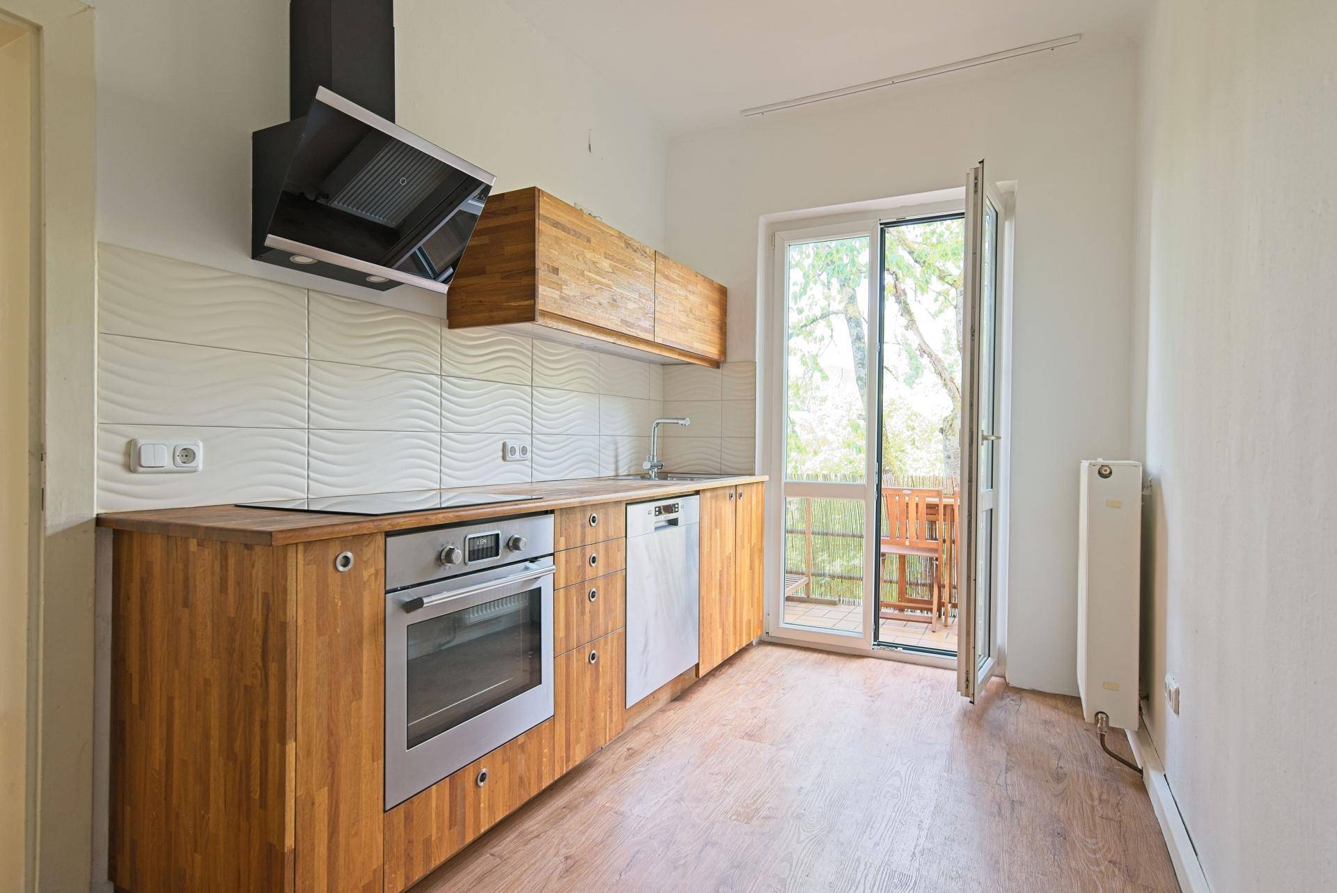 Funktionale Küche mit Holzschränken, integrierten Geräten und Zugang zu einem Außenbereich.
