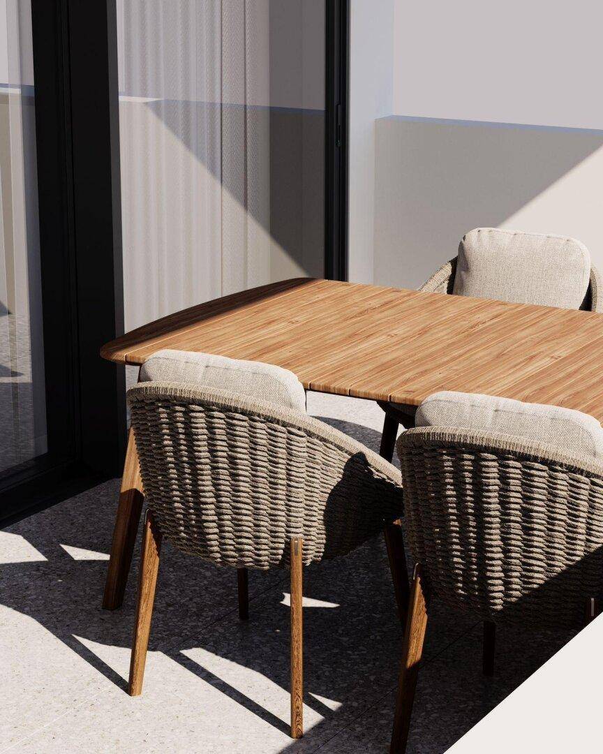 Sonniger Außenbereich mit Holztisch und bequemen Korbstühlen, ideal für Mahlzeiten im Freien.