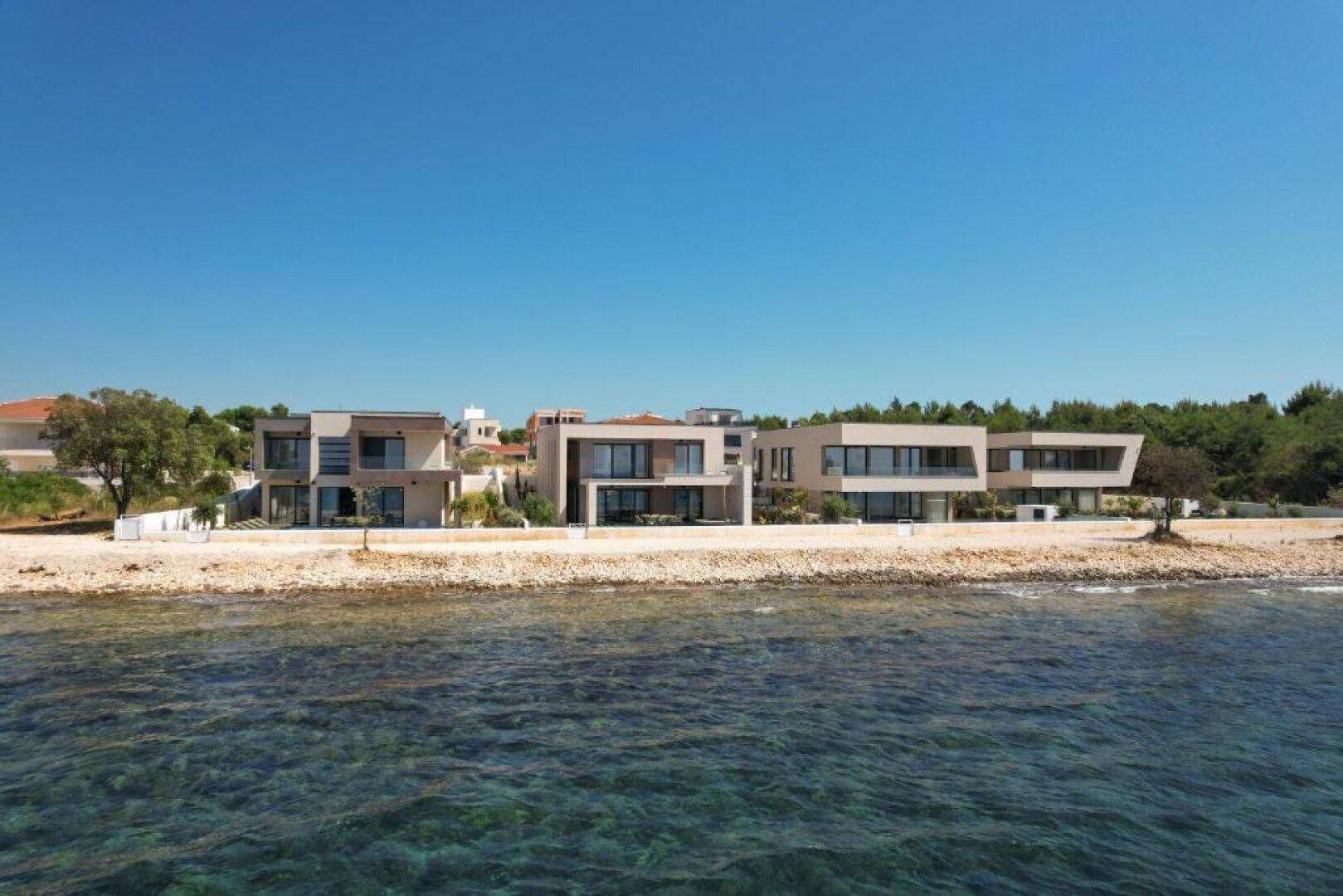 Ansicht der modernen Villen vom Meer aus, direkt am Strand gelegen mit klarem Wasser.