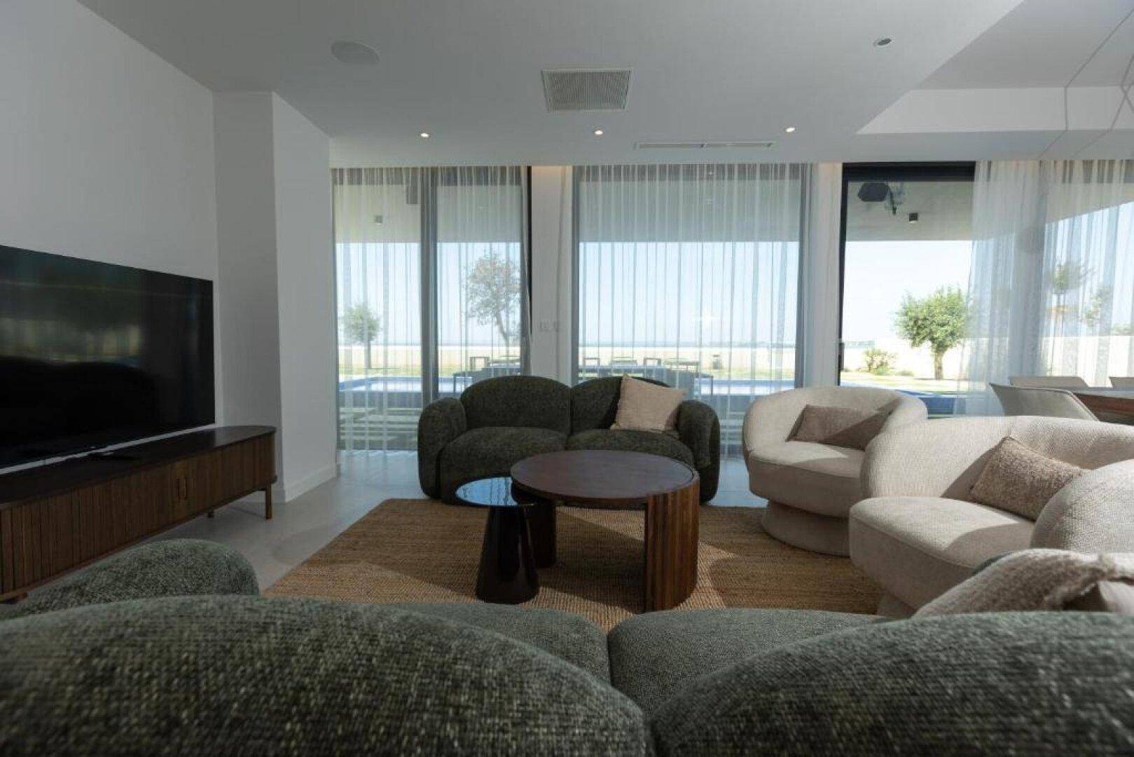Gemütliches Wohnzimmer mit modernen Sofas, großem Fernseher und weitem Meerblick durch die Fenster.