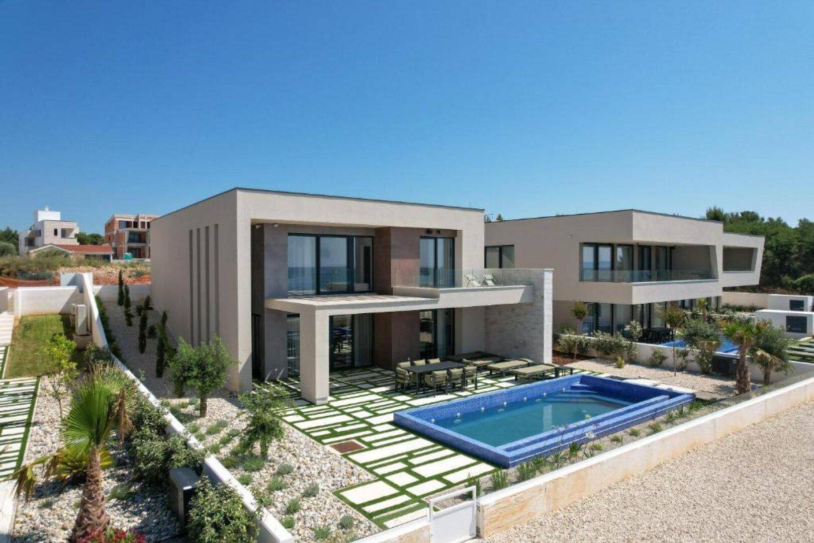 Luxuriöse Villa mit großem Poolbereich, Sonnenterrasse und mediterraner Bepflanzung.