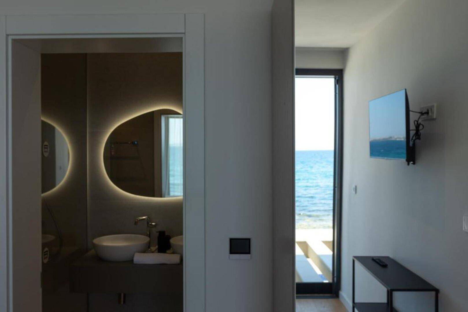 Heller Flur mit Zugang zu Bad und Schlafzimmer, mit Meerblick durch die Tür.
