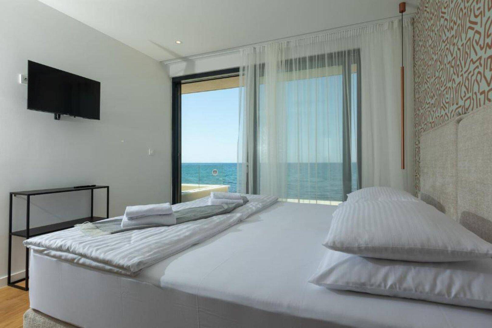 Komfortables Schlafzimmer mit Meerblick, großem Fenster und moderner Einrichtung.