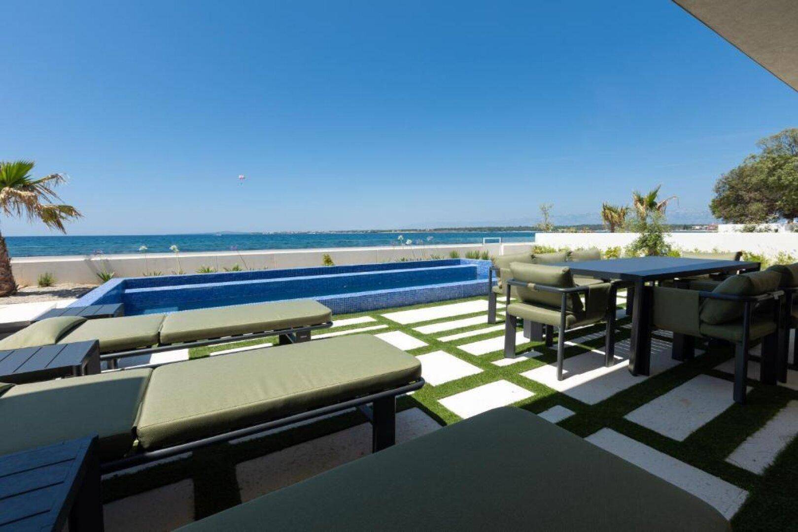 Geräumige Terrasse mit Lounge-Möbeln, Pool und direktem Blick auf das Meer.