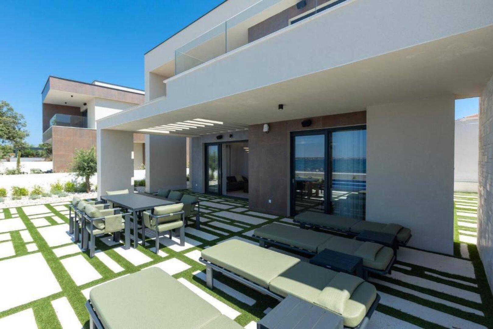 Überdachte Terrasse mit Essbereich und Sonnenliegen, ideal für Entspannung am Pool.